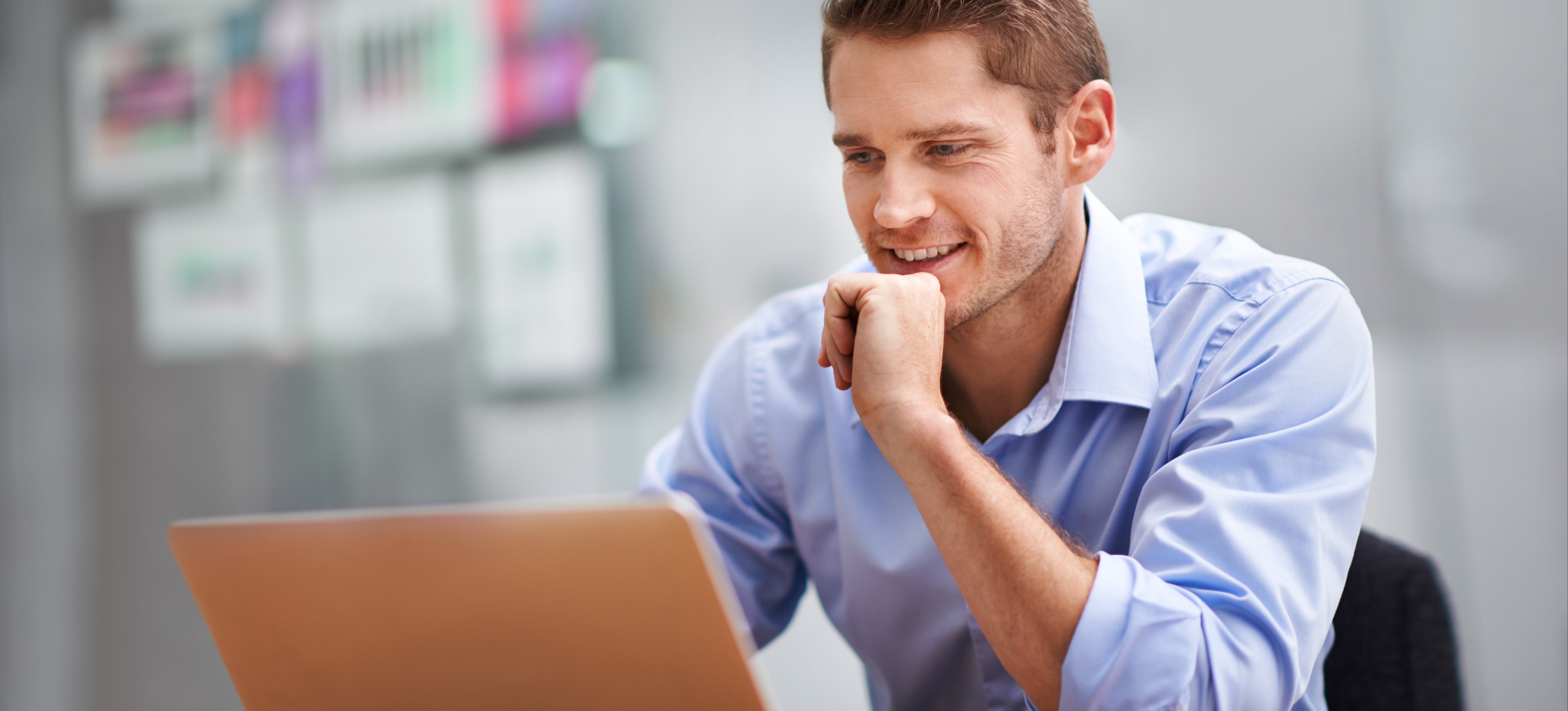 [Featured Image] A man is using e-learning on his laptop in his office to improve his skills.
