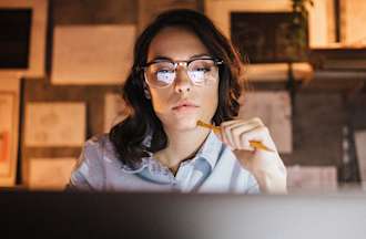 [Featured Image] A worker sits at their laptop and uses artificial intelligence to automate a repetitive task, realizing the benefits of AI. 