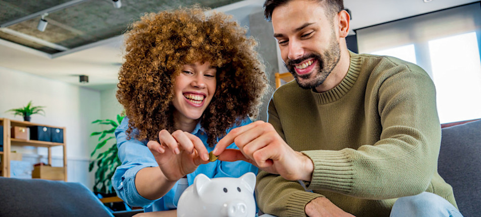 [Featured image]: Two people put coins in a piggy bank to demonstrate how understanding the time value of money impacts budgeting decisions.
