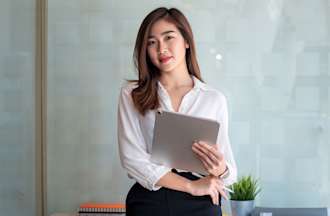 [Featured Image] A lady in business casual clothing is holding a tablet and pen.  