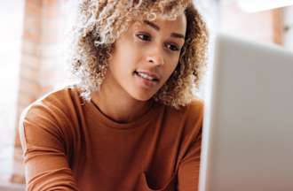 [Featured Image] A woman sitting at a computer serves as the superuser for her office.