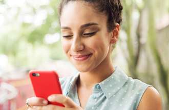 [Featured Image] A woman smiles while experiencing haptic feedback while using her smartphone.