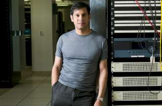[Featured image] A computer forensic investigator in a gray t-shirt leans against a computer server in a data center. 