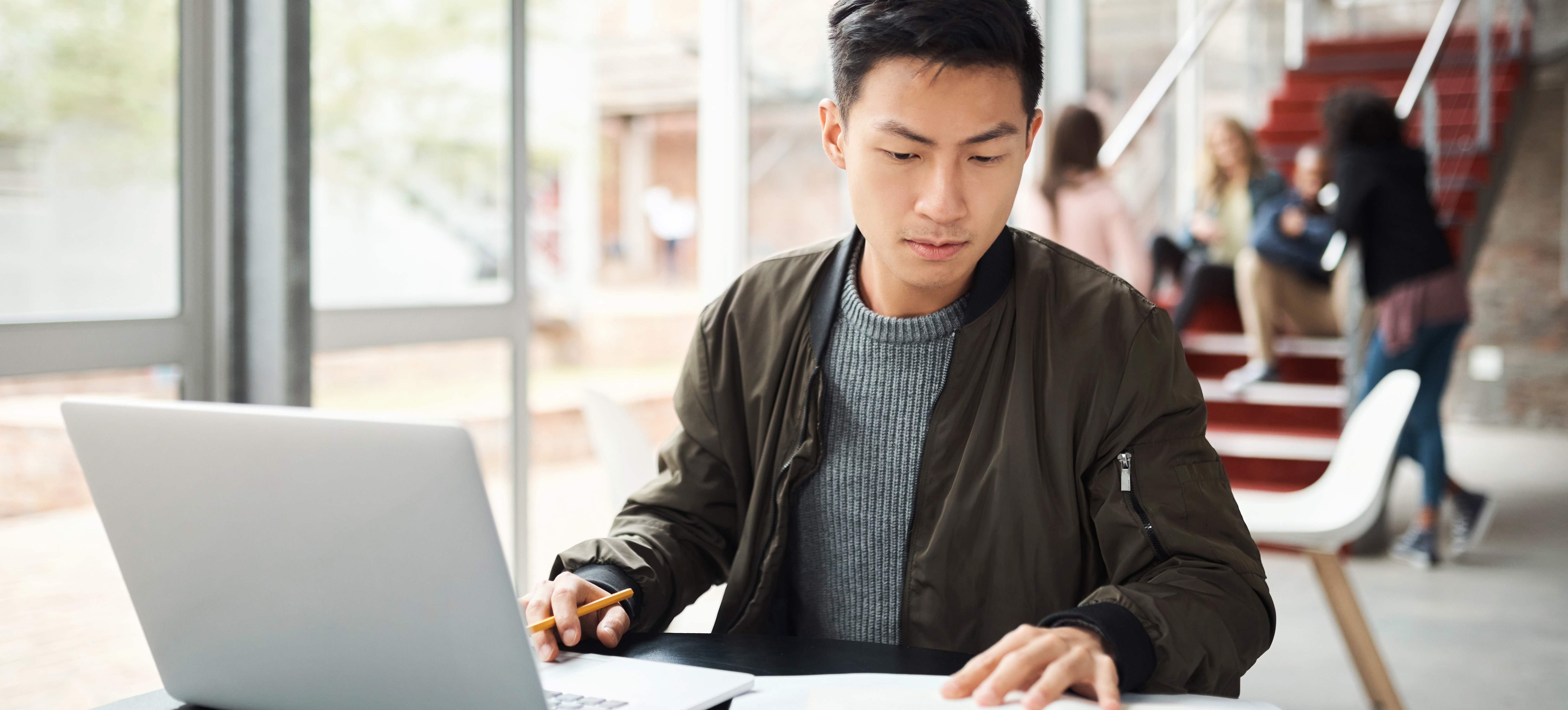 [Featured Image] A student studies for their master's degree at a laptop in a library despite their low GPA.