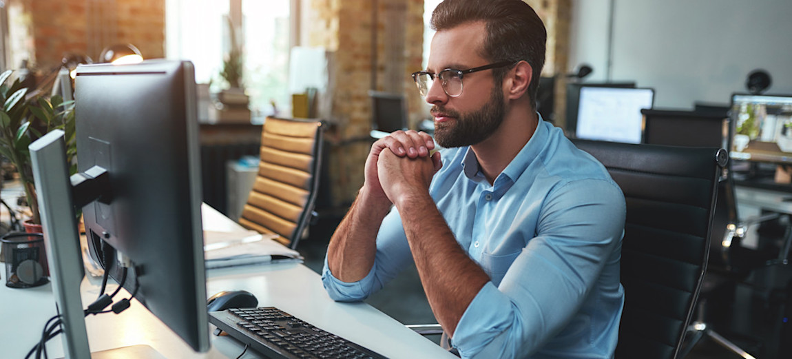 [Featured Image] A machine learning engineer sits in an attractive office, looking at their computer screen and pondering classification versus regression in machine learning.
