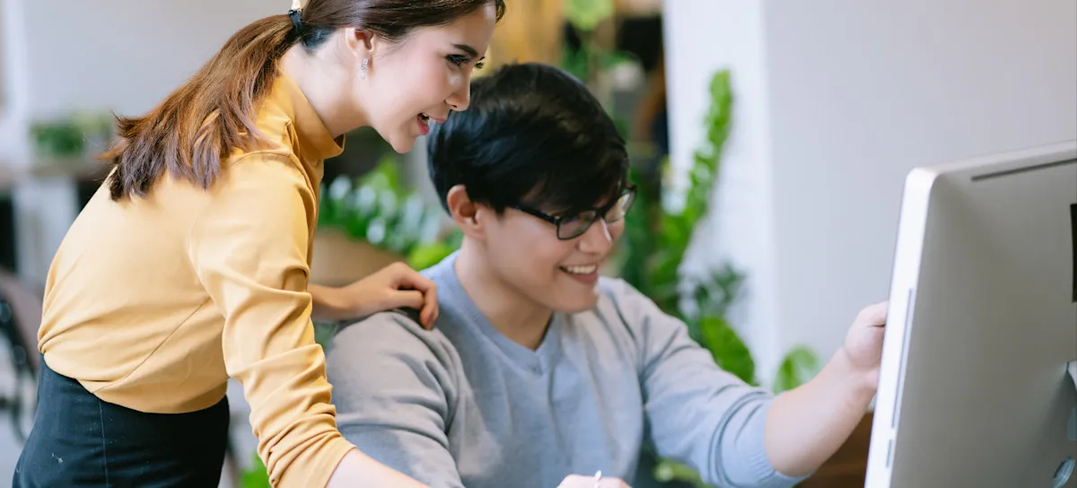 [Featured image] Two business partners look at a computer as they add a user to Google Analytics.