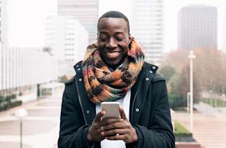 [Featured image] An IT support specialist is researching subnet masking on their phone while standing outside. 