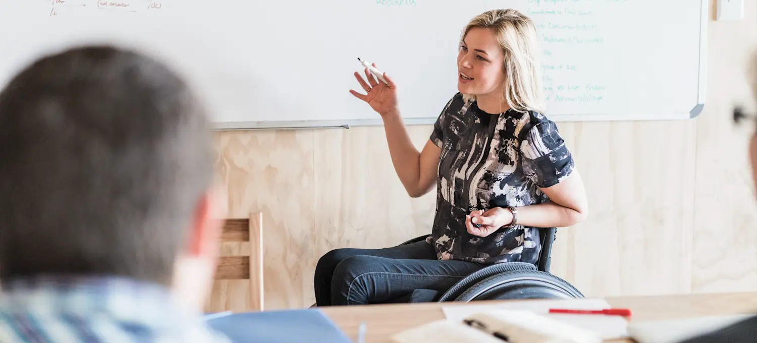 [Featured Image] A product manager leads a meeting with a product lifecycle management (PLM) team to discuss the development of a product as it goes through the product lifecycle stages. 