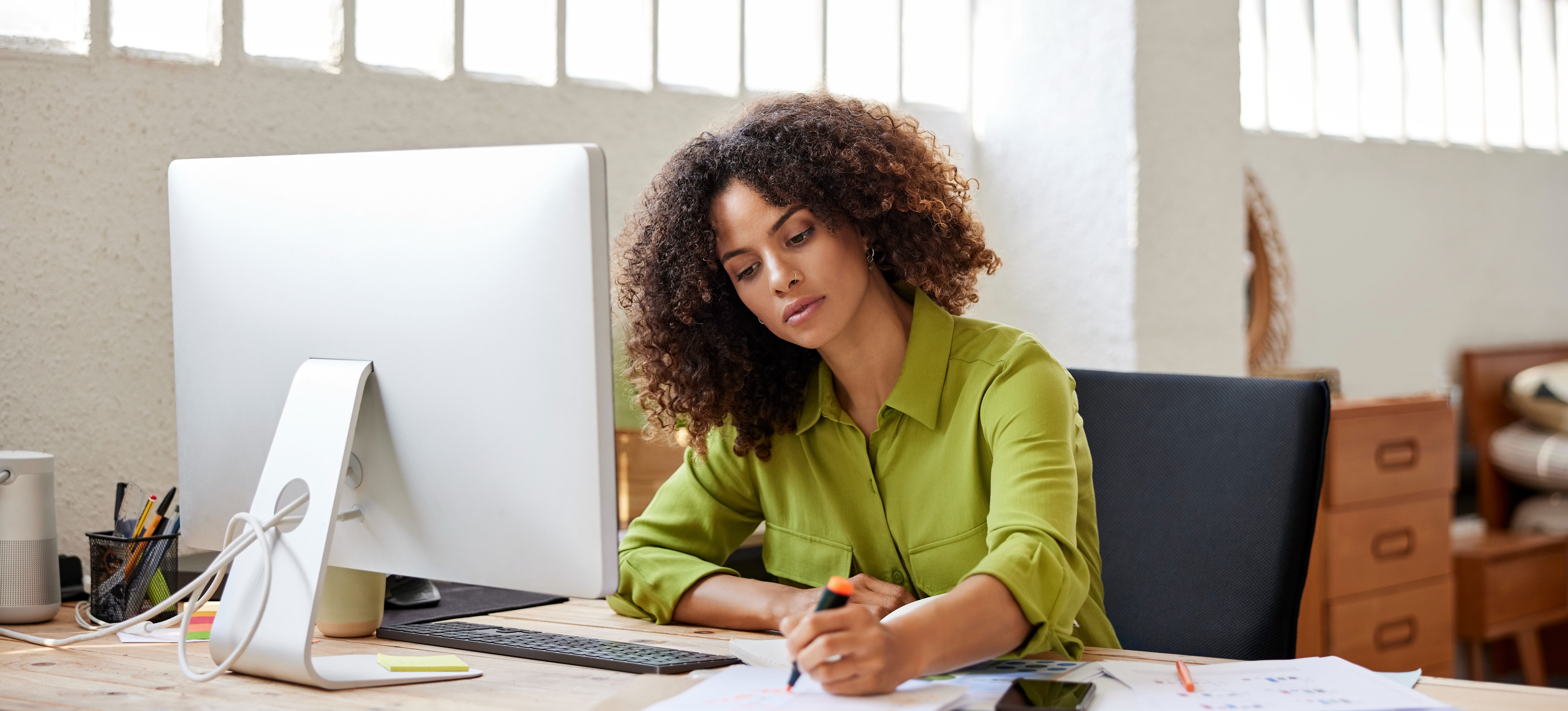 [Featured Image] A person sits at their organized desk in their home office and works productively.
