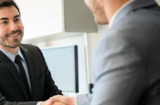 [Featured Image] A man wearing a suit shakes hands with an interviewer during his job interview for one of the DHS jobs to which he applied.
