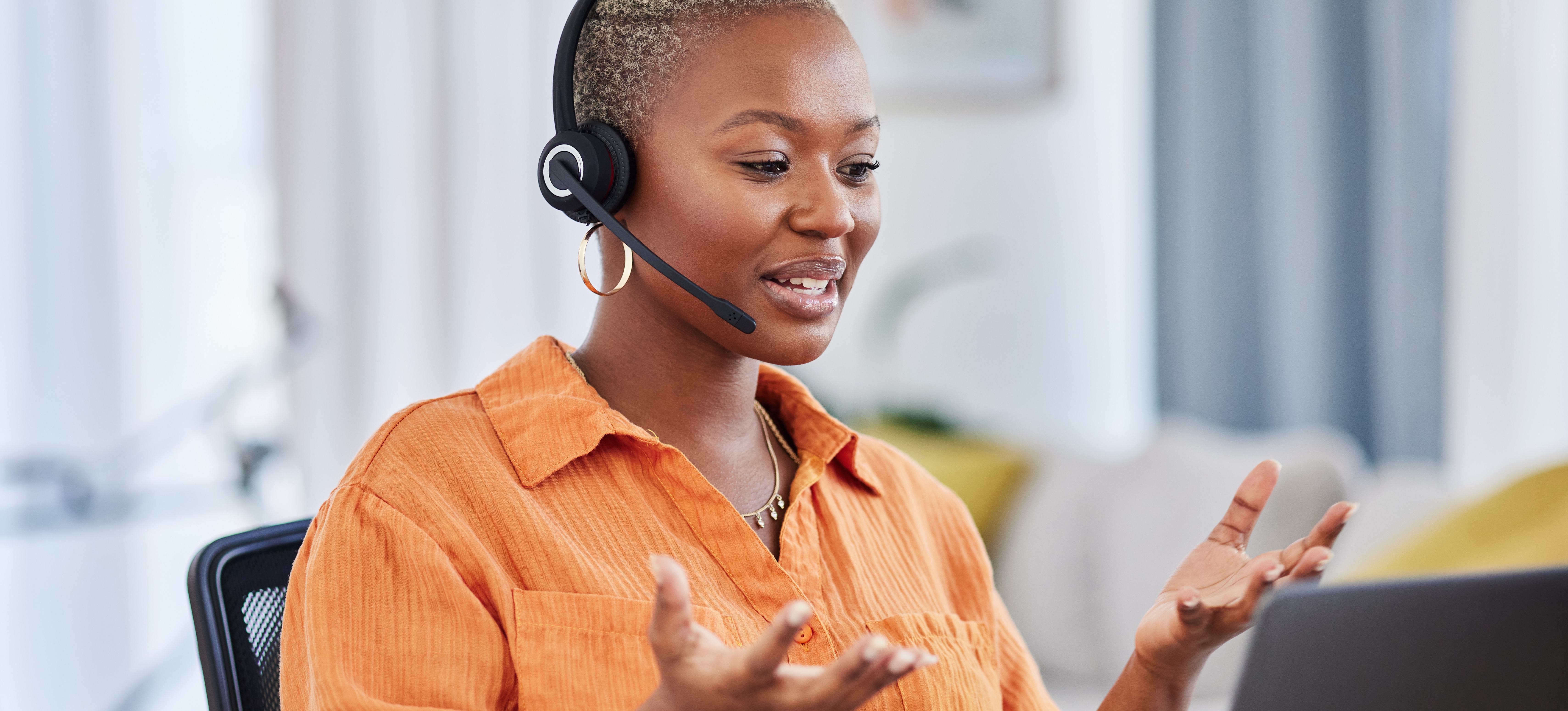 [Featured Image] A customer service representative sits at a workspace with a laptop and headset, assisting a customer.