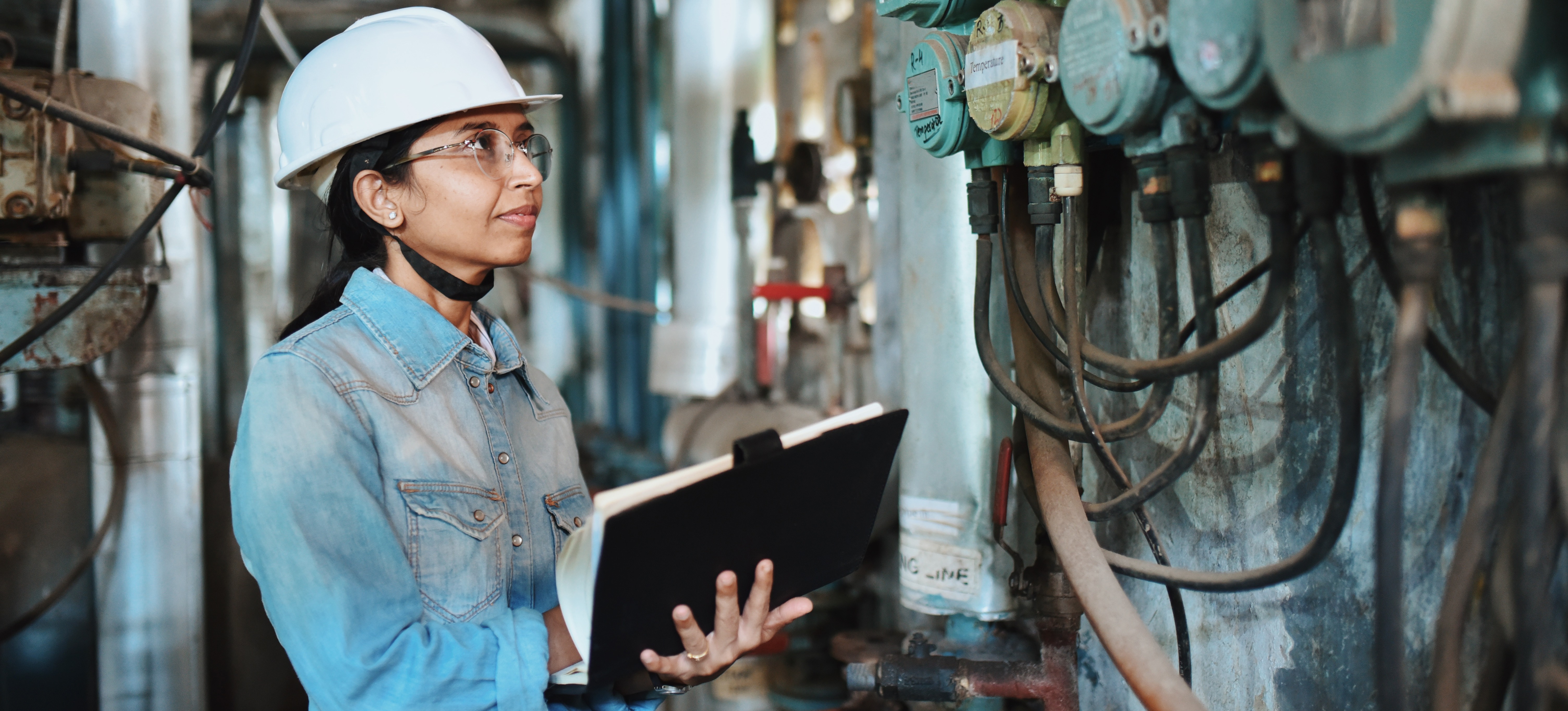 [Featured image] An engineer in a blue jumpsuit and white hard had examines a job site.