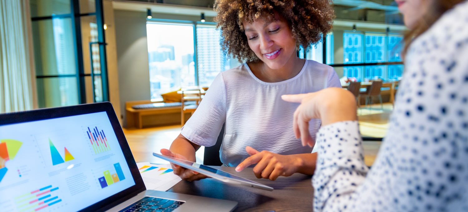 [Featured image] Two marketers sit at a laptop in the office and review predictive analytics examples to help determine which customers to target.