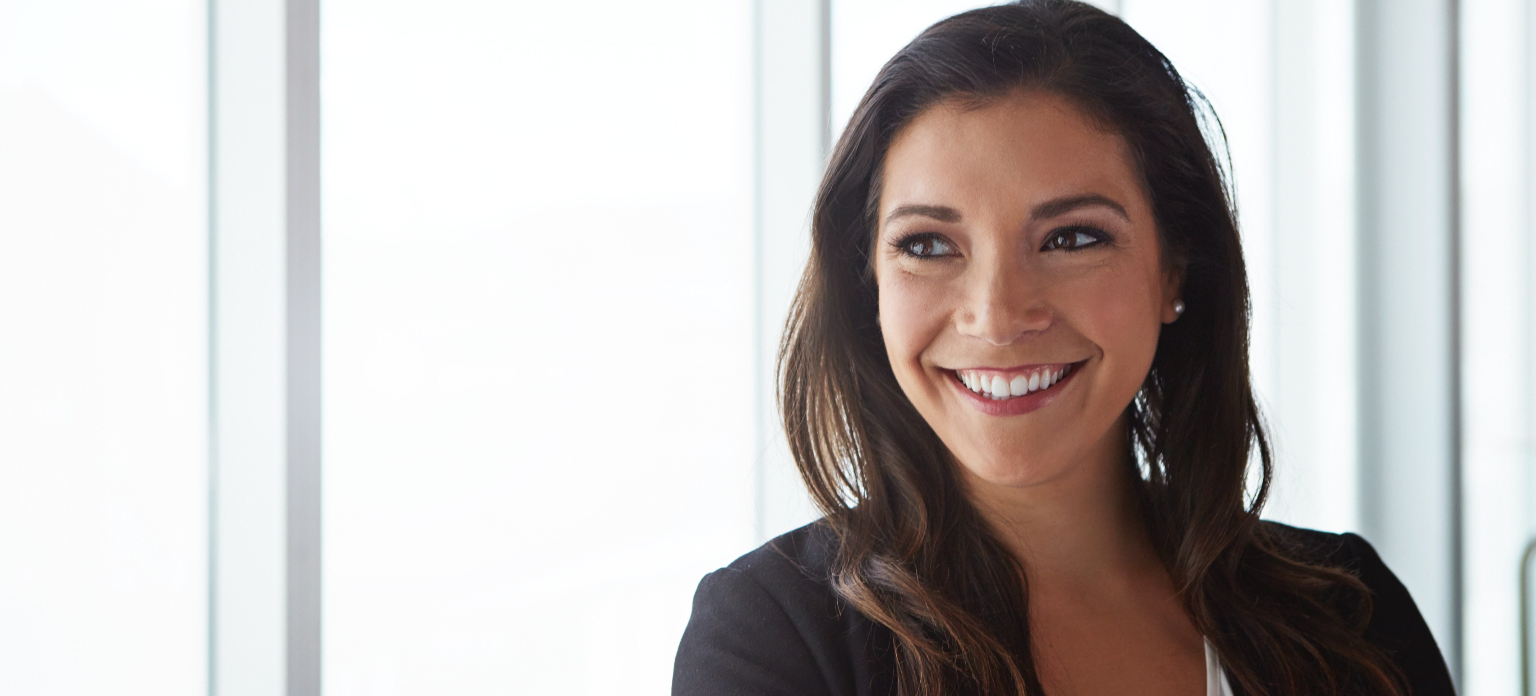 [Featured image] A smiling businessperson contemplates the advantages of an MBA salary while standing in front of large windows in an office.
