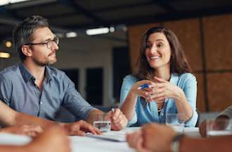 [Featured Image]  A group of people are having a meeting at a table.