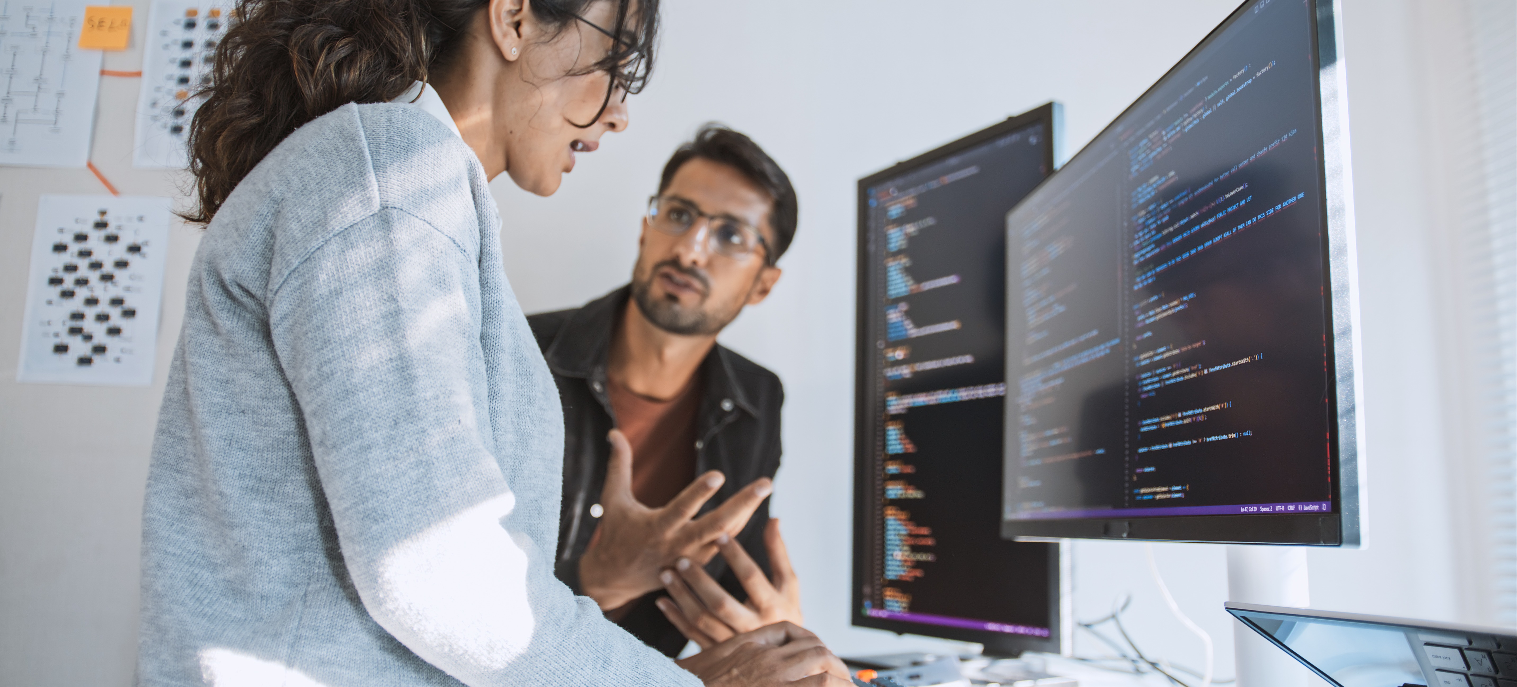 [Featured Image] NLP professionals collaborating on code, with one software engineer pointing at the screen while discussing the natural language processing algorithms with their colleague in a tech workspace.
