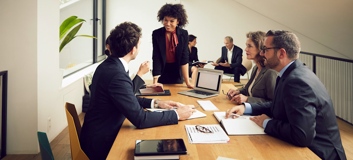 [Featured Image] A smiling lawyer, who is a philosophy graduate, is listening to a discussion with their colleagues during a meeting in an office.