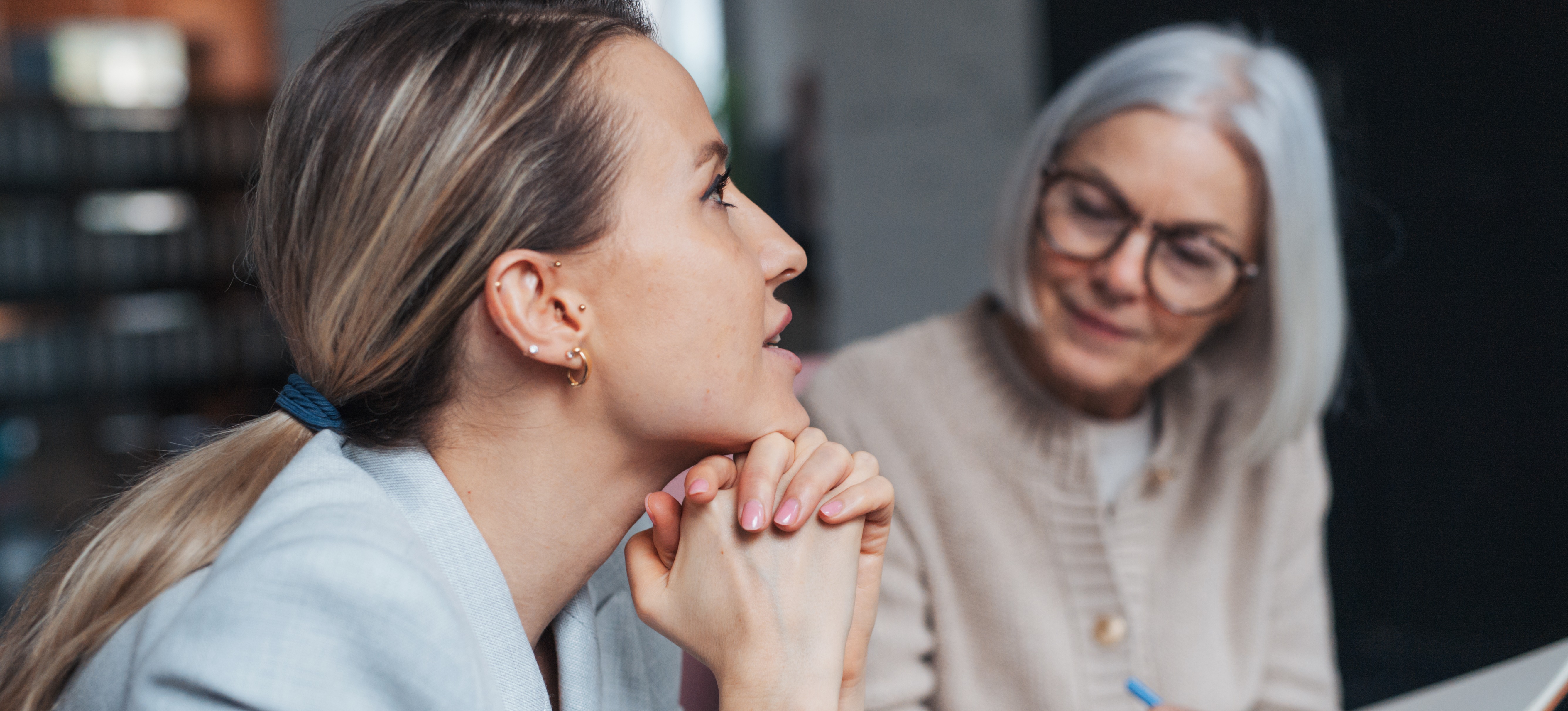 [Featured Image] A life coach takes notes in a journal as they listen to their client.
