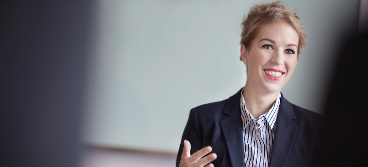 [Featured image] A HR consultant, wearing a dark jacket and a blue striped shirt, is sitting at a table.