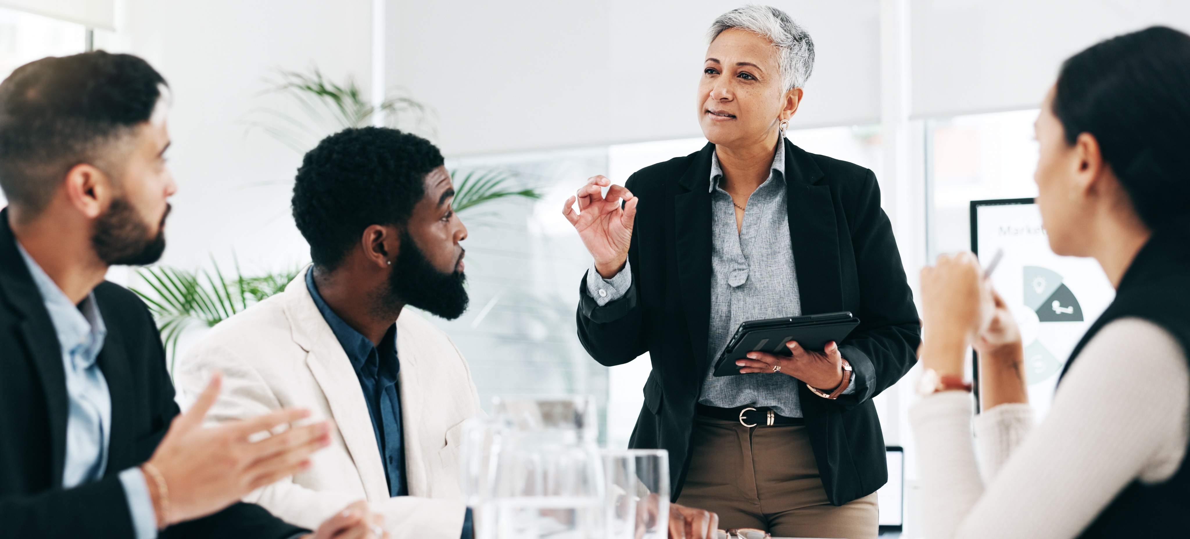 [Image en vedette] Un PDG se tient devant son équipe dans une salle de conférence où se déroule une formation à la direction d'entreprise.