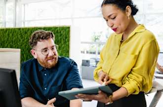 [Featured Image] Two employees discuss Address Resolution Protocol in the office. 