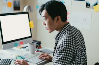 [Featured Image] A man in a checkered shirt searches the web for React developer salary insights. 
