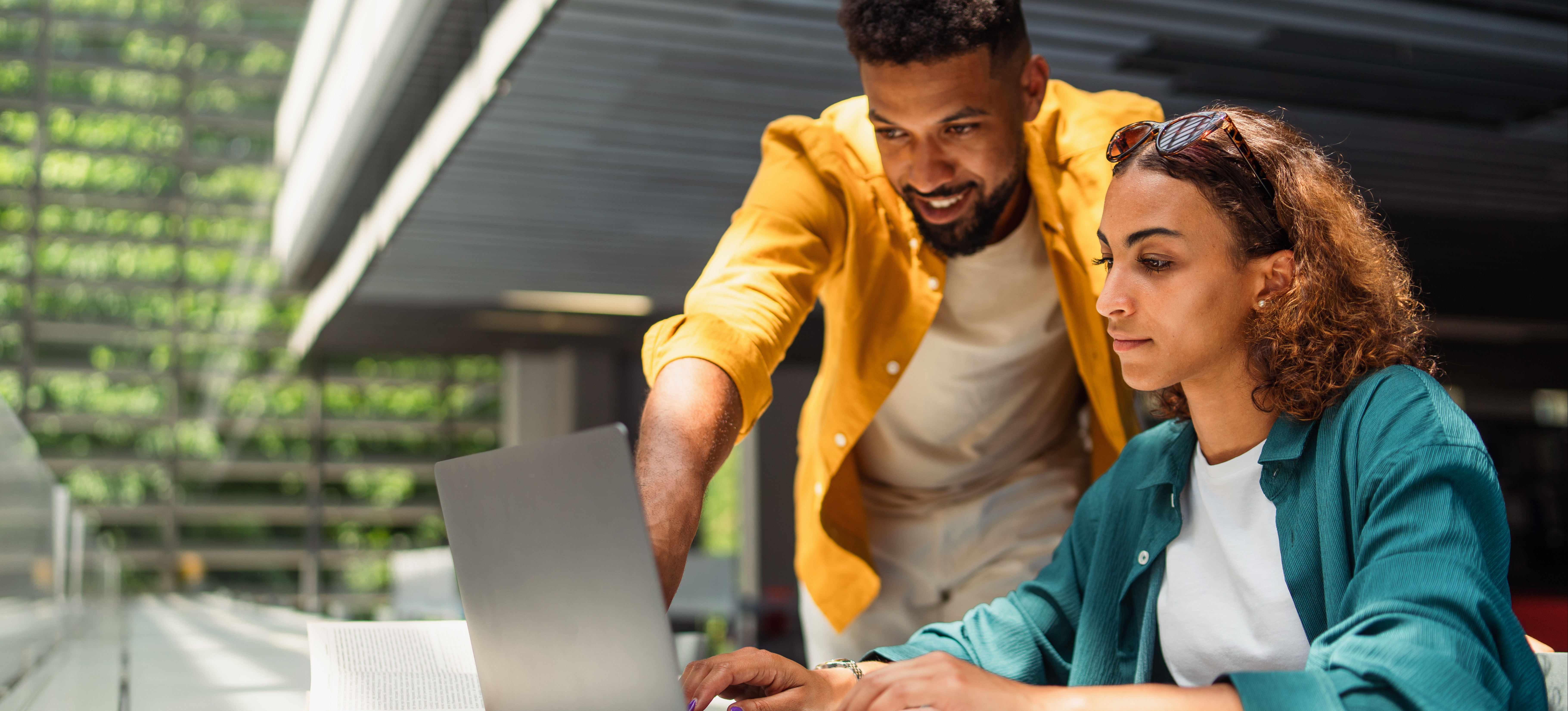 [Featured Image] A creative project manager shows a creative brief to a coworker using a laptop.