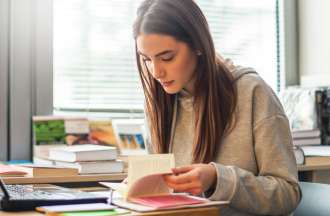 [Featured image] A technical writer works from home and reads a book while at their desk. 