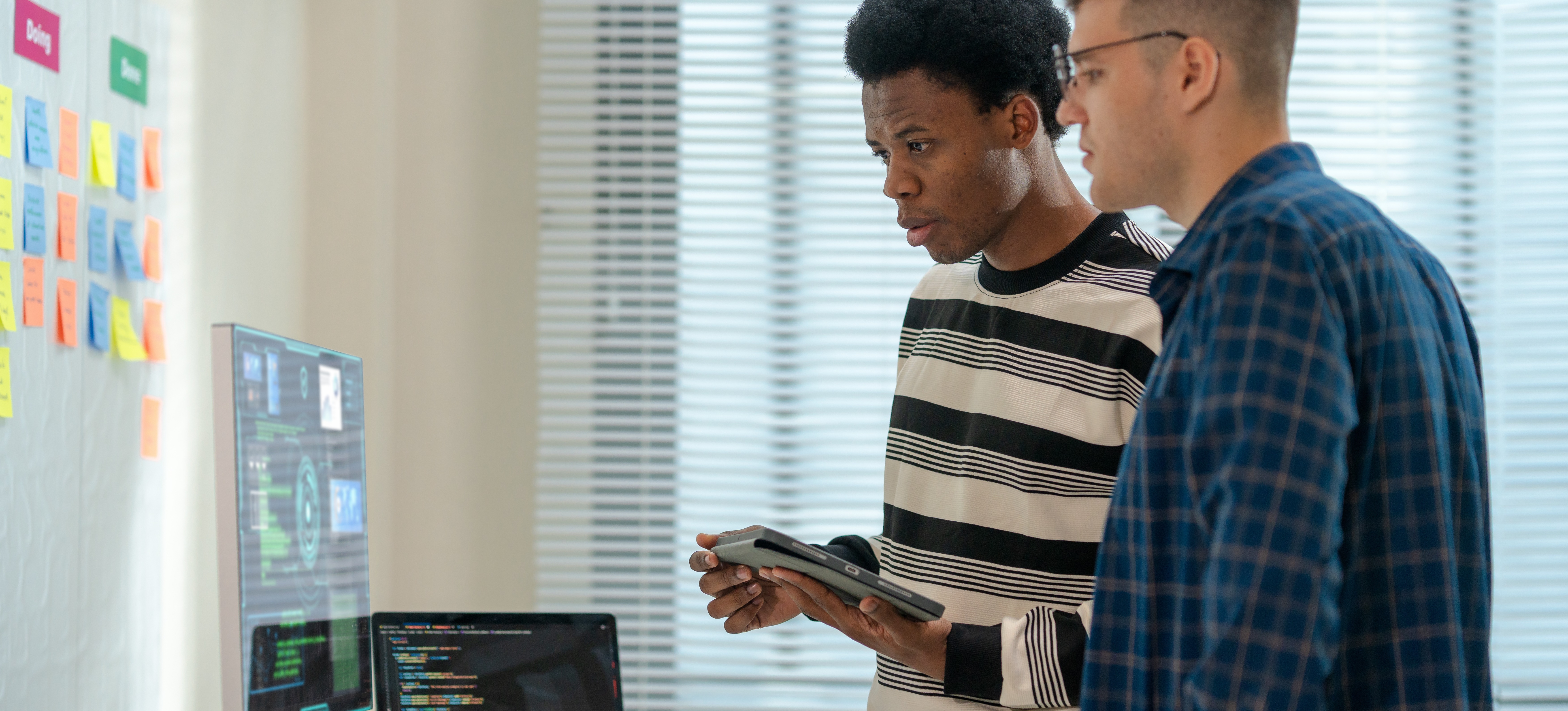 [Featured Image] Professionals in a workplace, reviewing the PC and discussing the best MLOps platforms.