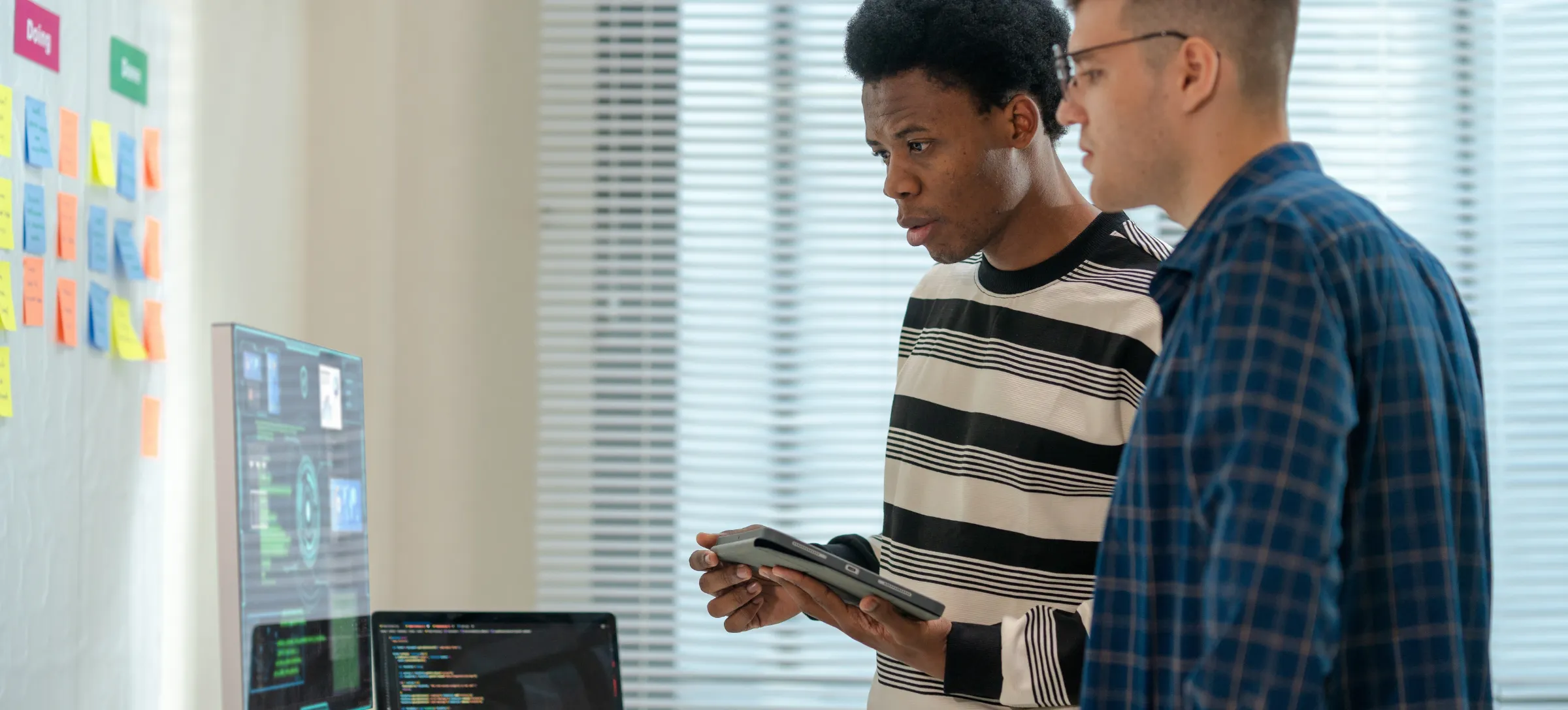 [Featured Image] Professionals in a workplace, reviewing the PC and discussing the best MLOps platforms.