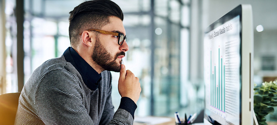 [Featured Image] A digital marketer looks at graphs on a computer created by topic modeling.
