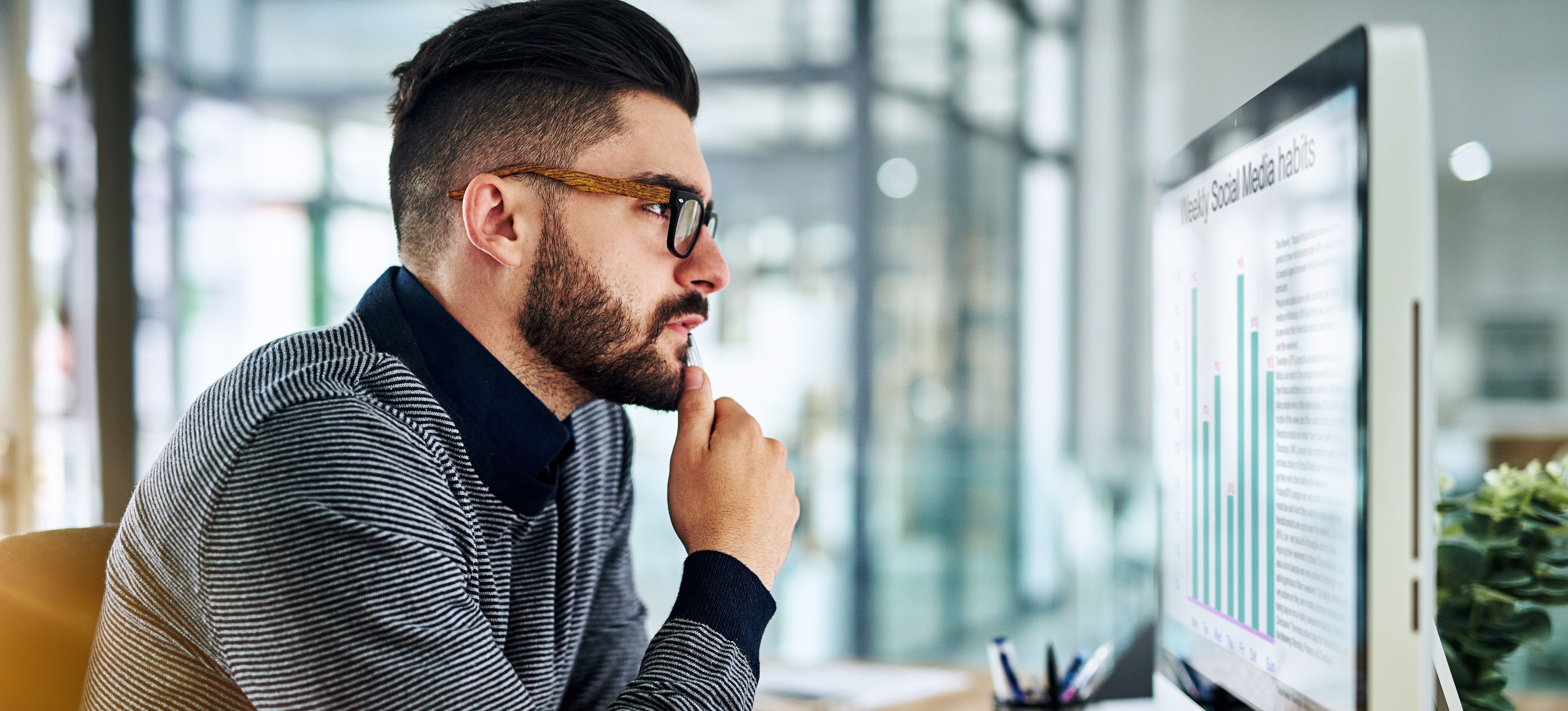 [Featured Image] A digital marketer looks at graphs on a computer created by topic modeling.
