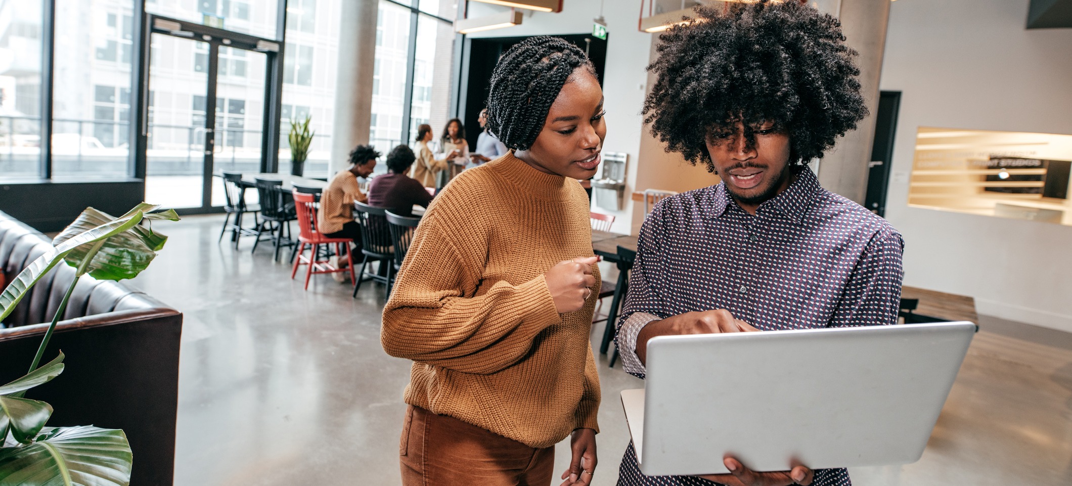 [Featured Image] Two operations associates review information on a laptop in an office.