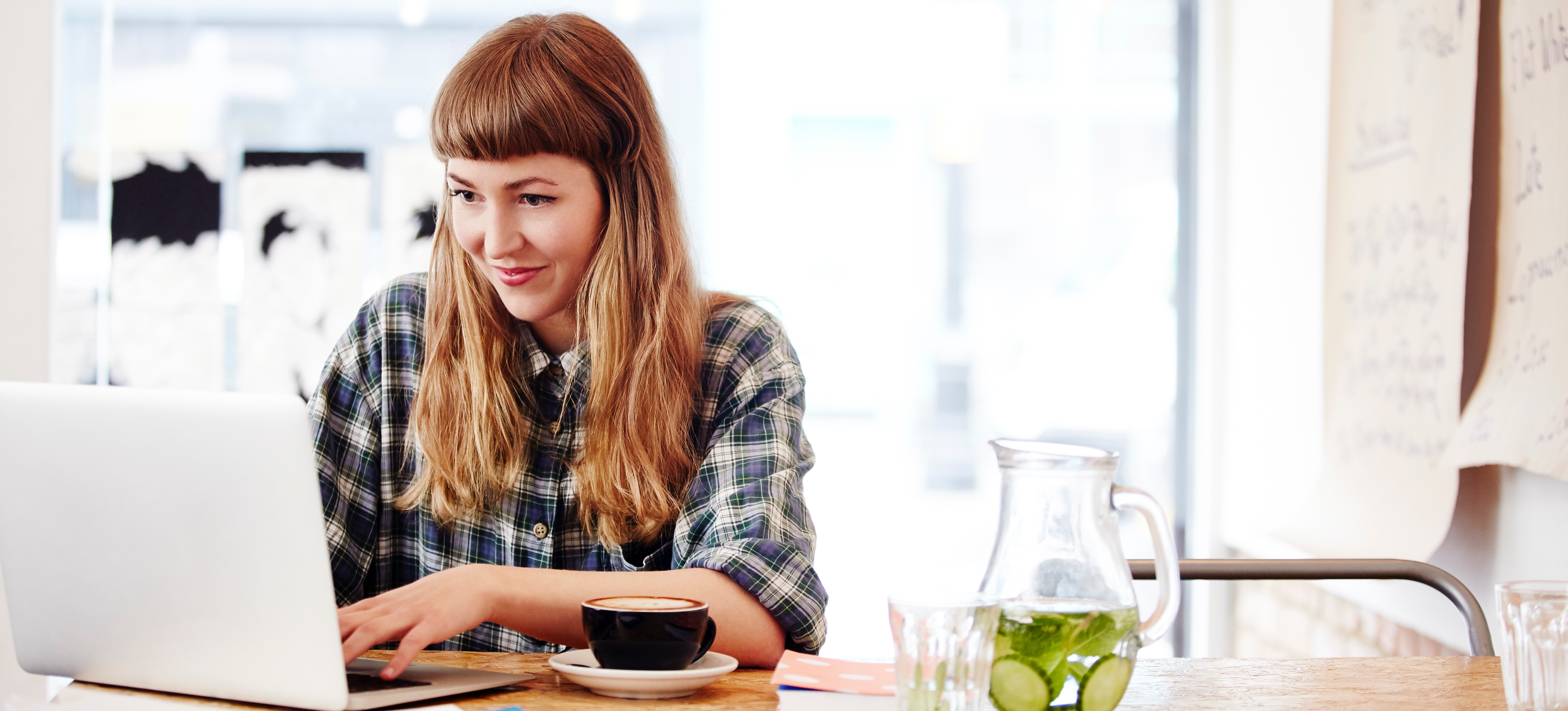 [Featured Image] A learner researches high-paying IT jobs on a laptop in a brightly-lit coffee shop to discover their path forward.