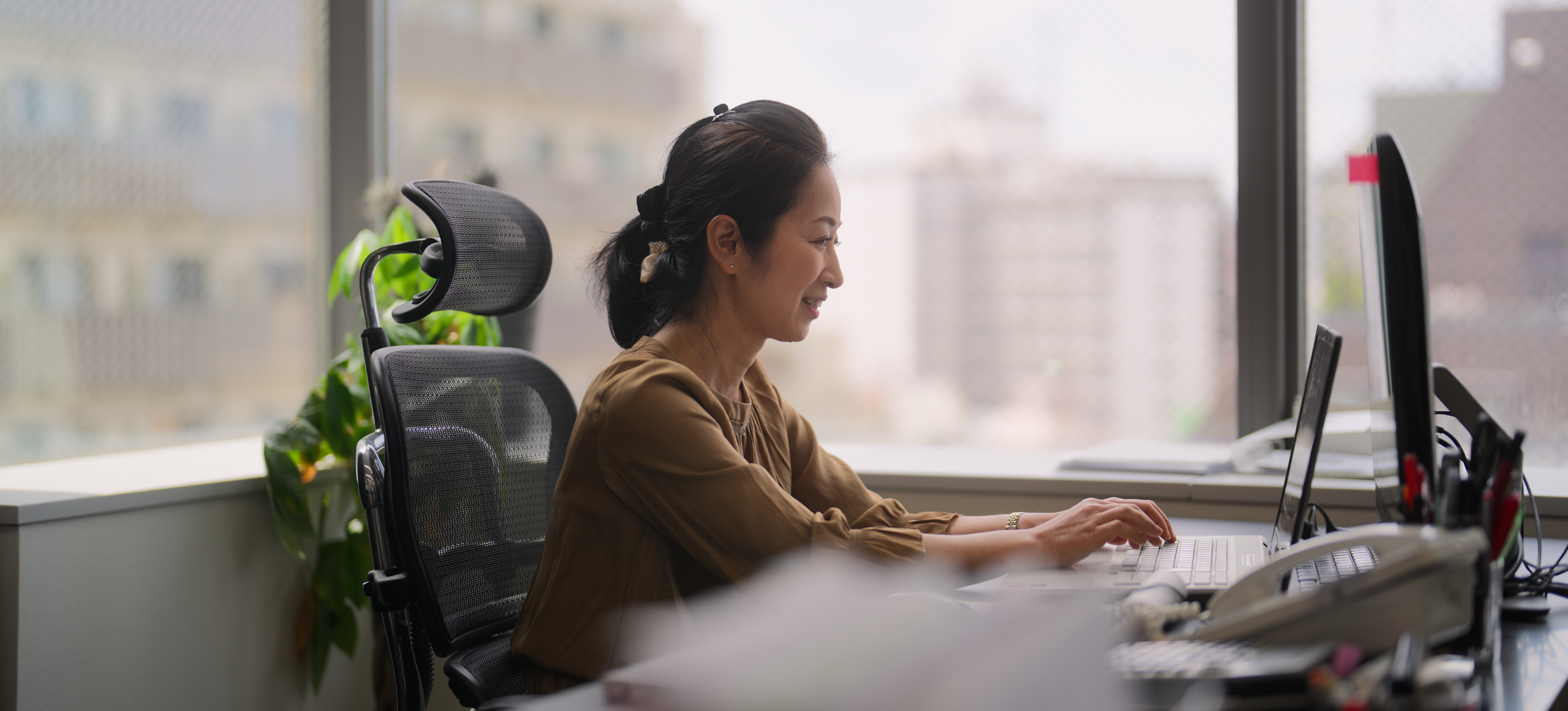[Featured Image] A person sits at their desk with a laptop and is using a wide area network to communicate with their colleagues.