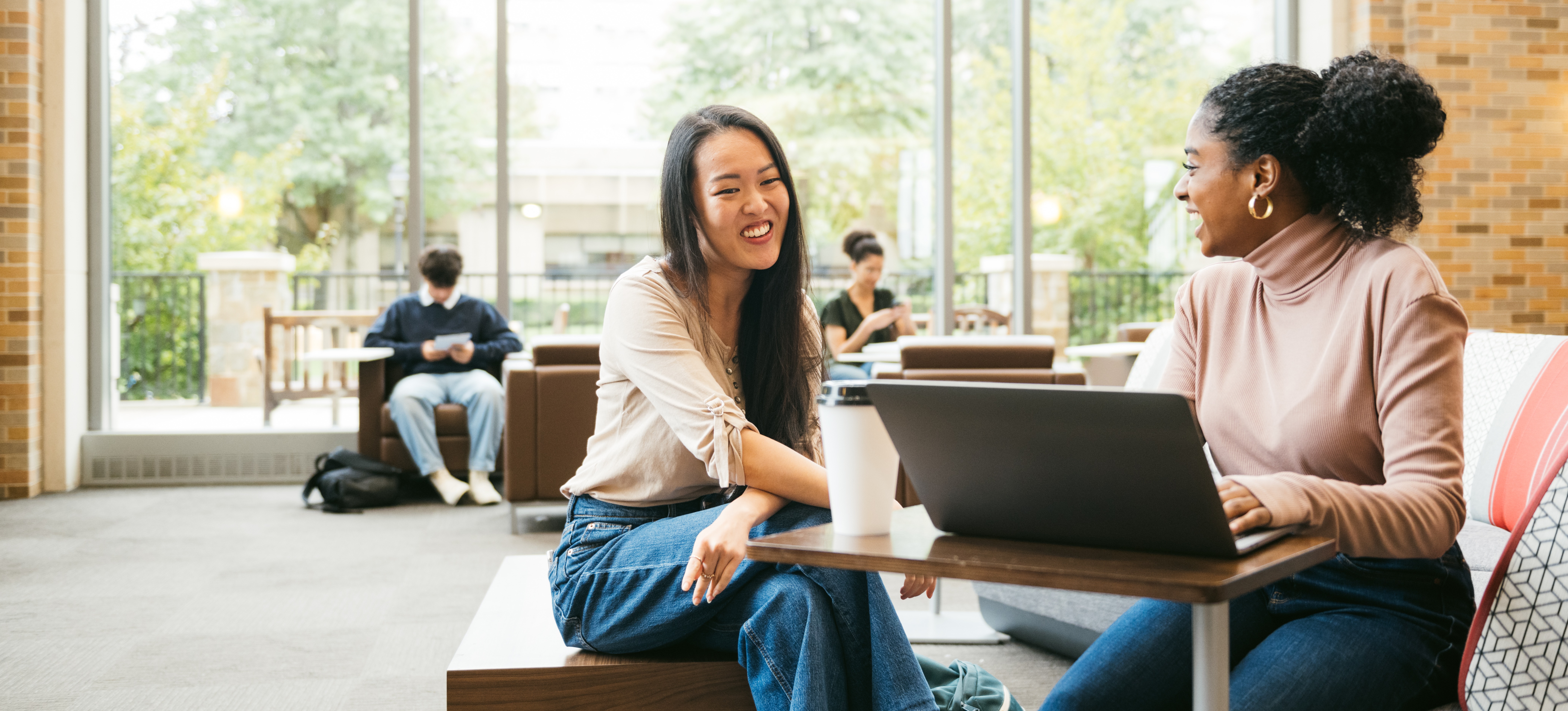 [Feature Image] Two learners study together for a course that’s part of their associate degree in business program. 
