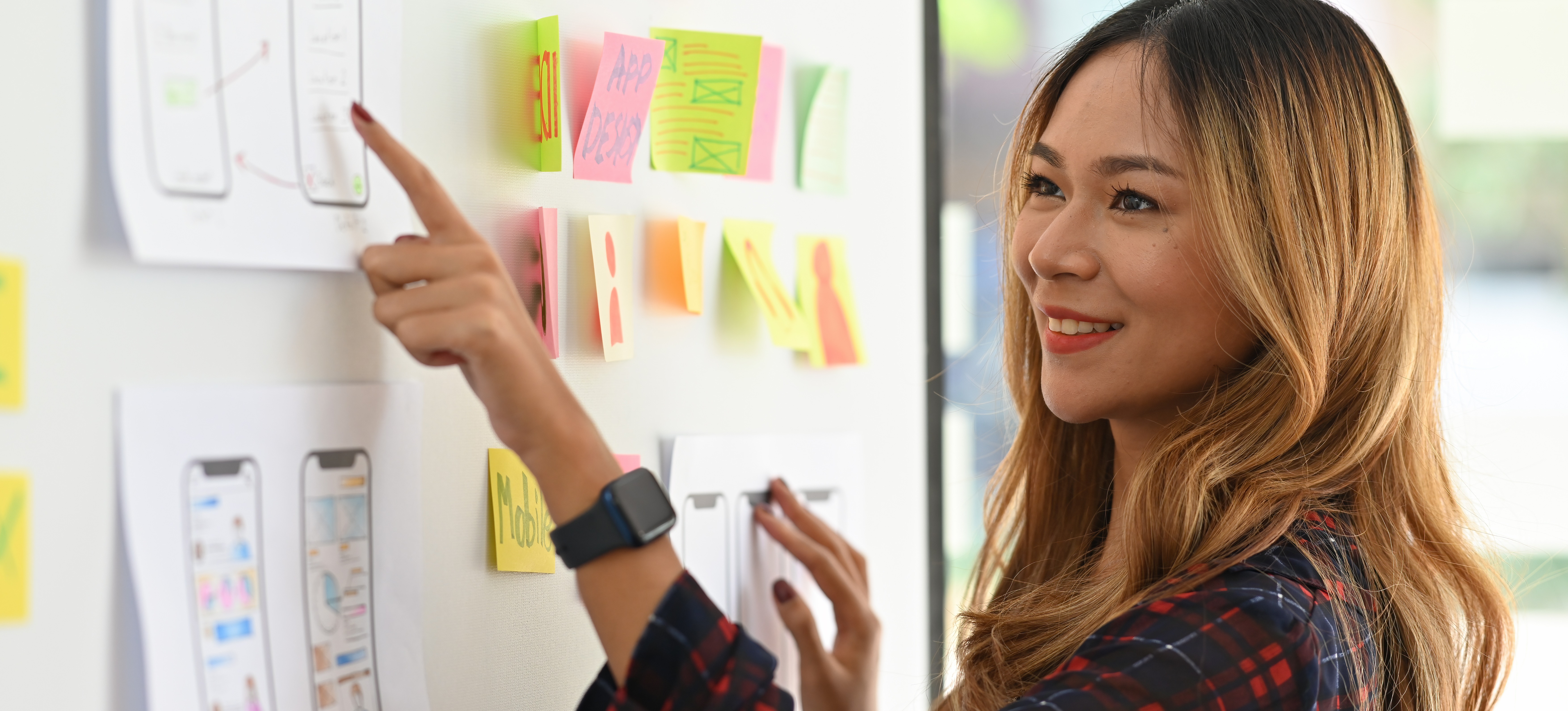 [Featured Image] A UX designer points to a mockup of an app design made using low-fidelity wireframe tools.
