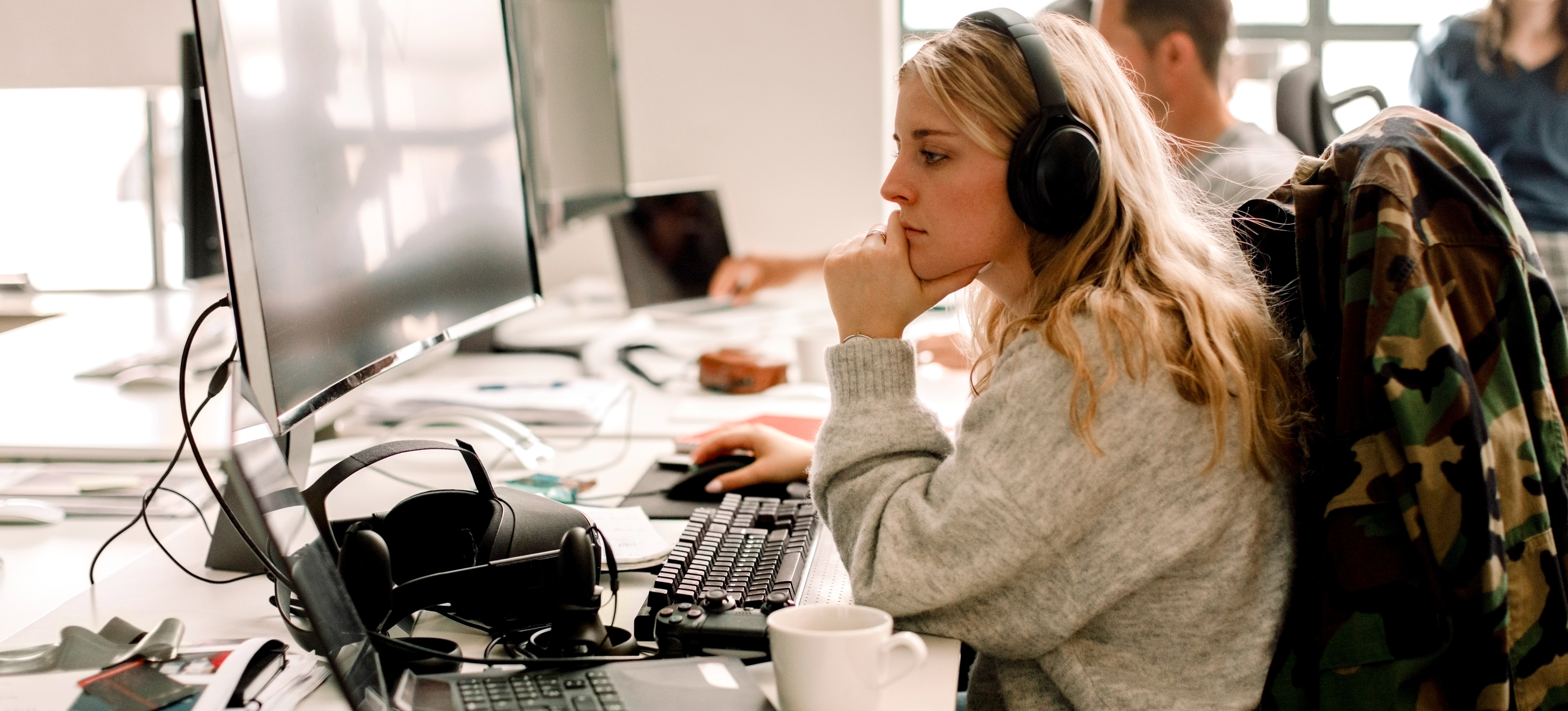 [Featured image] A vigilant woman, wearing a jacket and headphones, closely monitors her computer screen for signs of cyber threats.