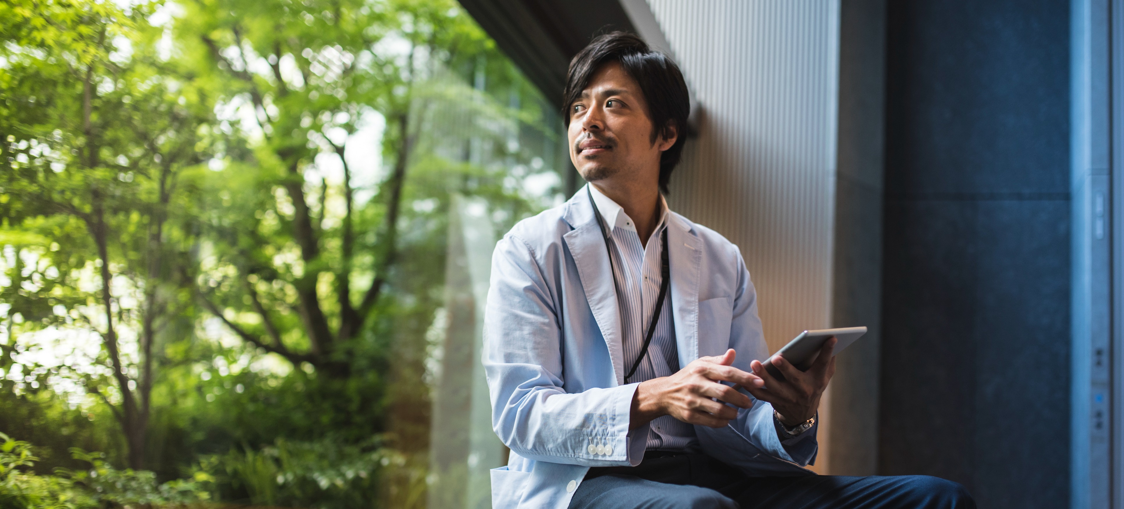 [Featured image] Man at window working on a tablet