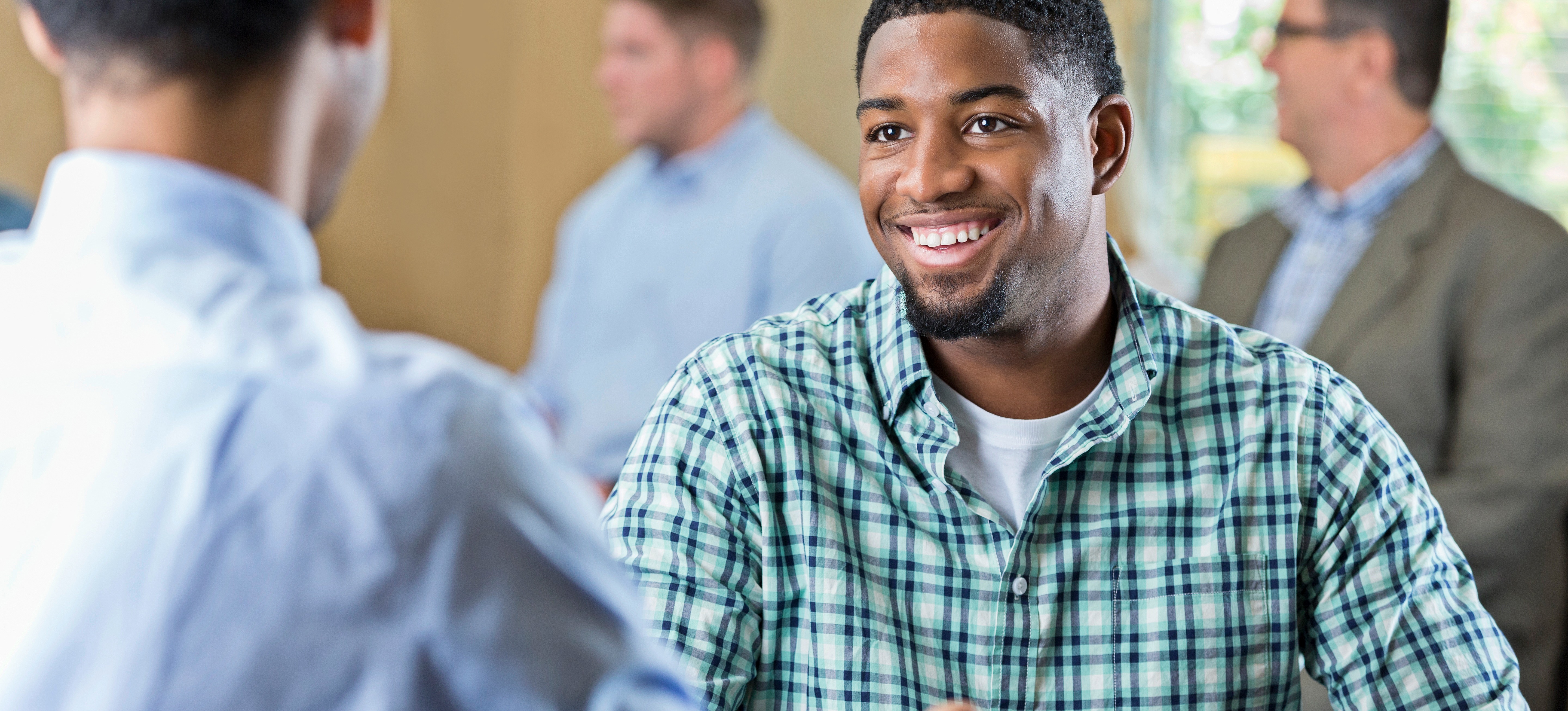 [Featured Image] A smiling job candidate with a personal profile CV talks to a potential employer in an office setting.
