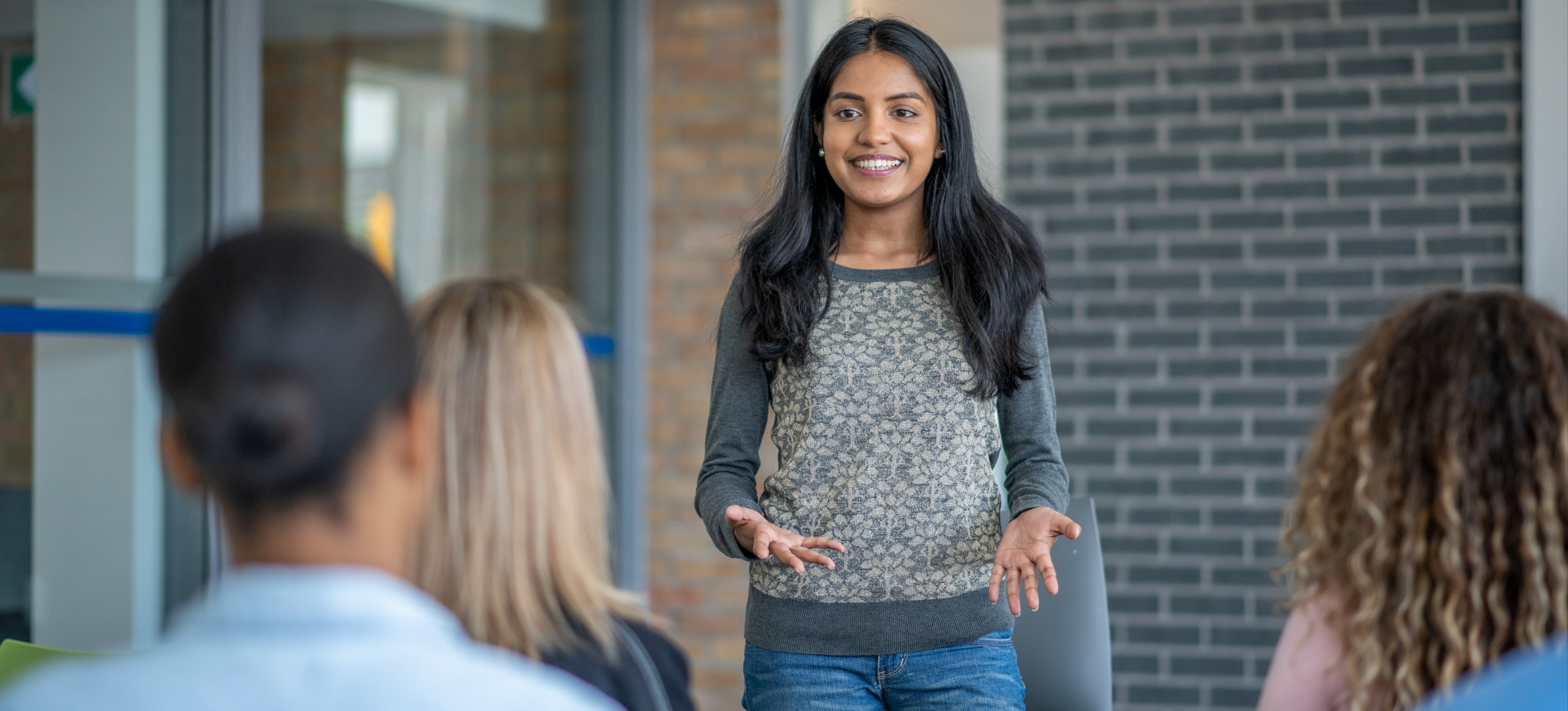 [Featured Image]: A young professional presents to a group after learning how to overcome imposter syndrome.

