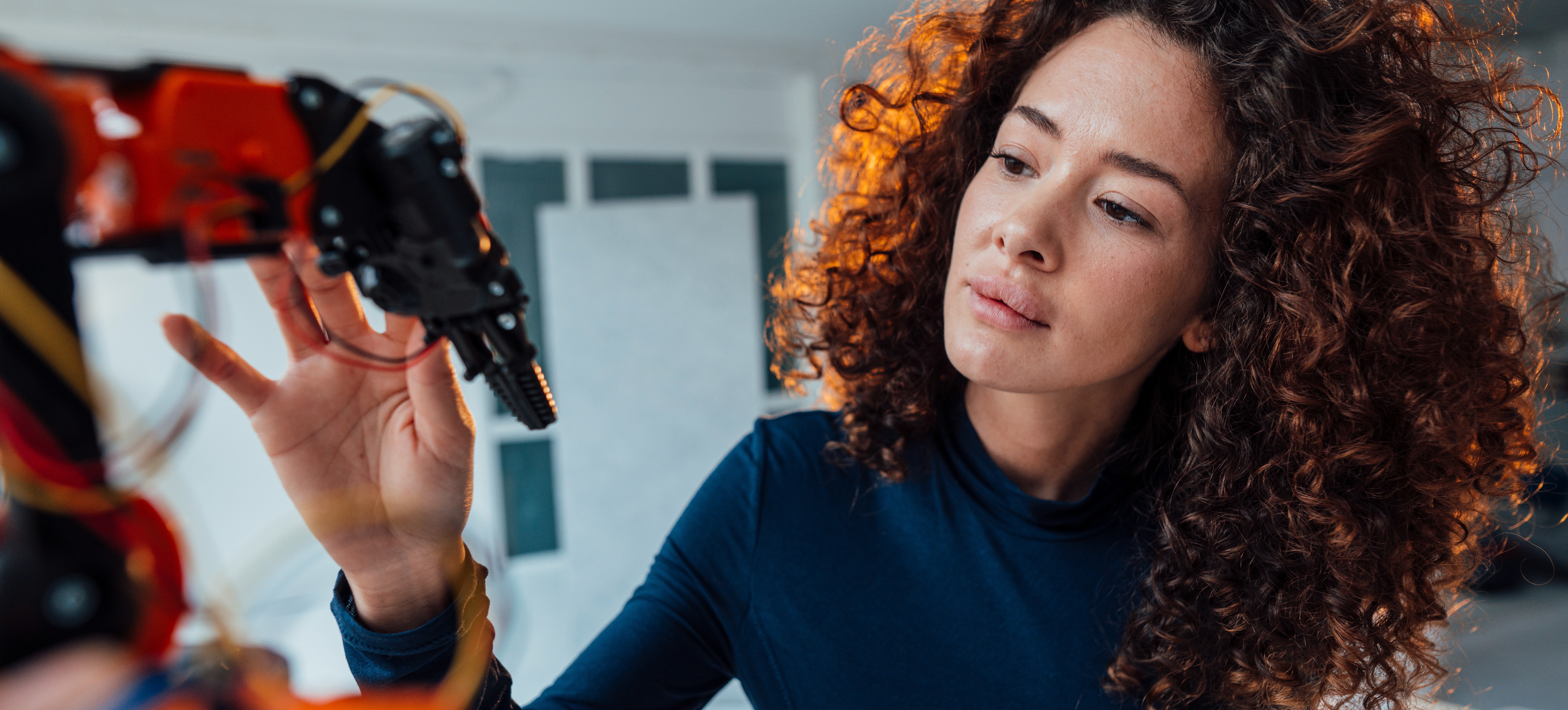 [Featured Image] An engineer is learning the differences between AI and robotics while observing a robotic arm in a lab.
