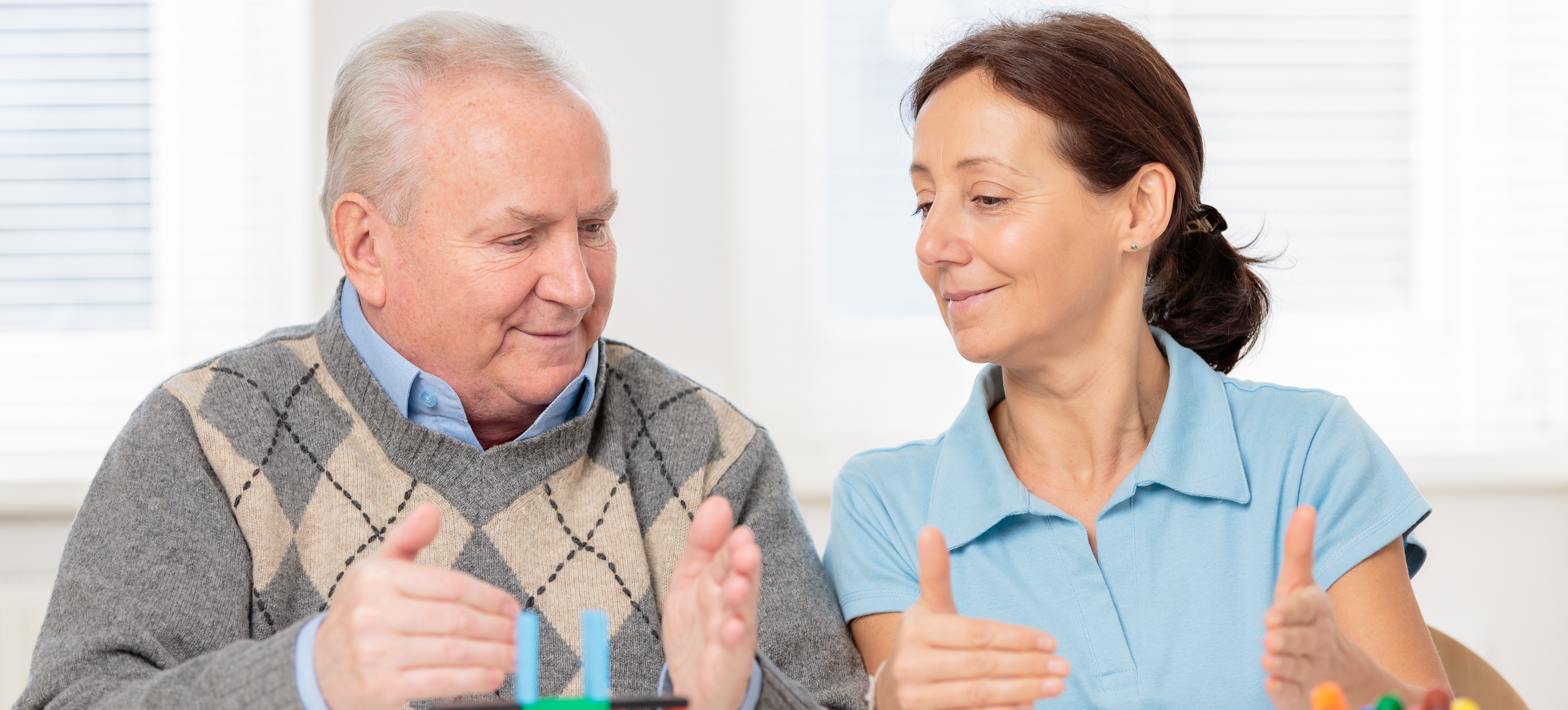 [Featured Image] An occupational therapy assistant uses blocks to work with a patient in a nursing home.   