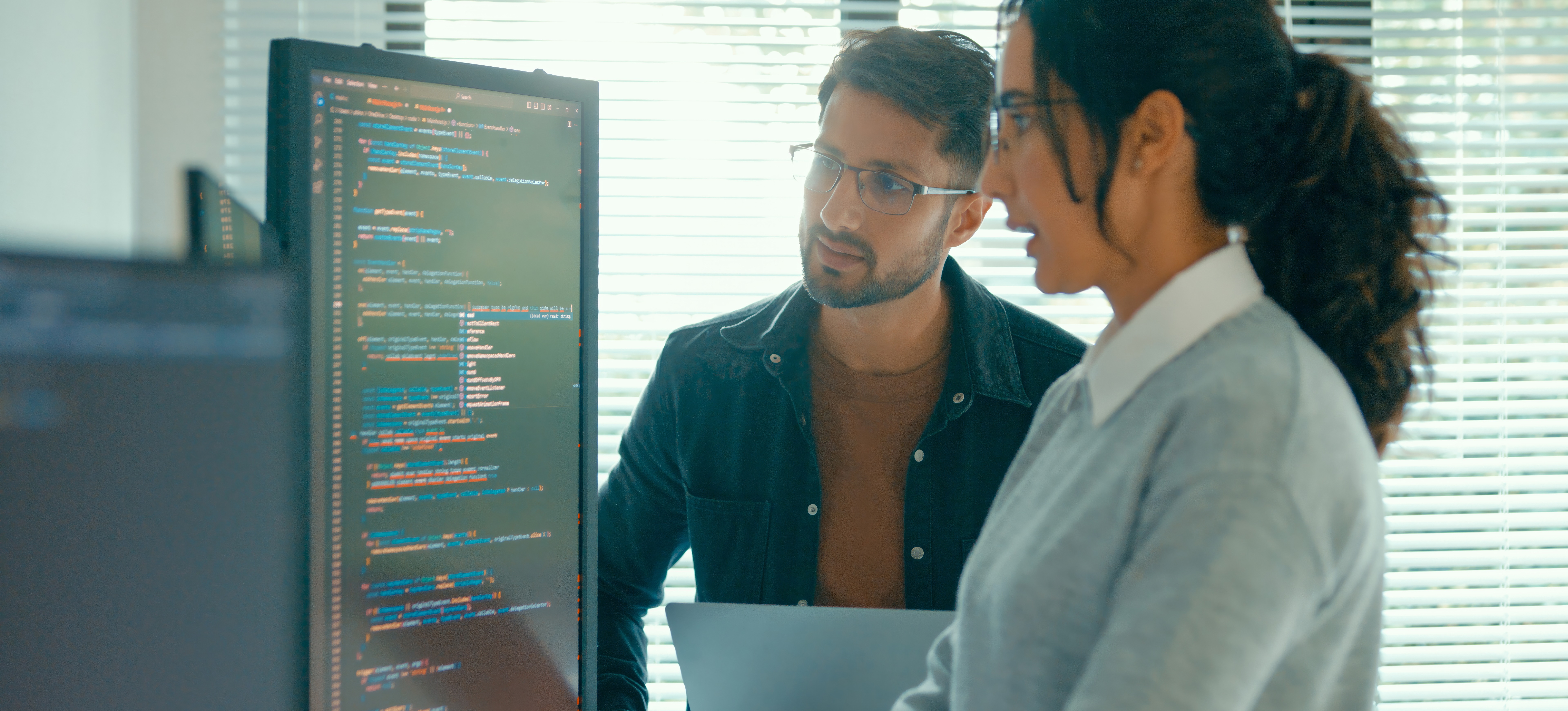 [Featured Image] Two data scientists look at a computer screen as they discuss data integrity.
