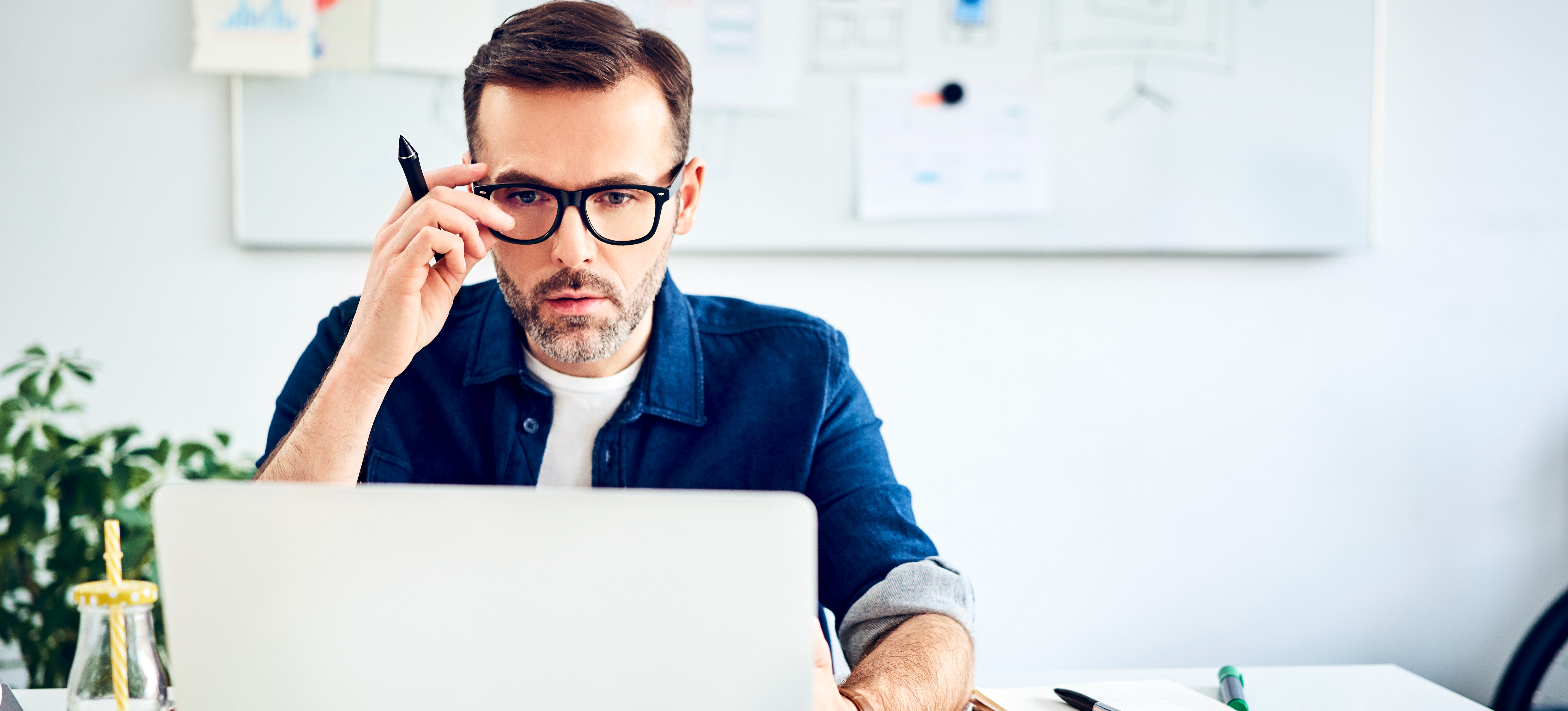 [Featured Image] A man wearing glasses works on a laptop computer.
