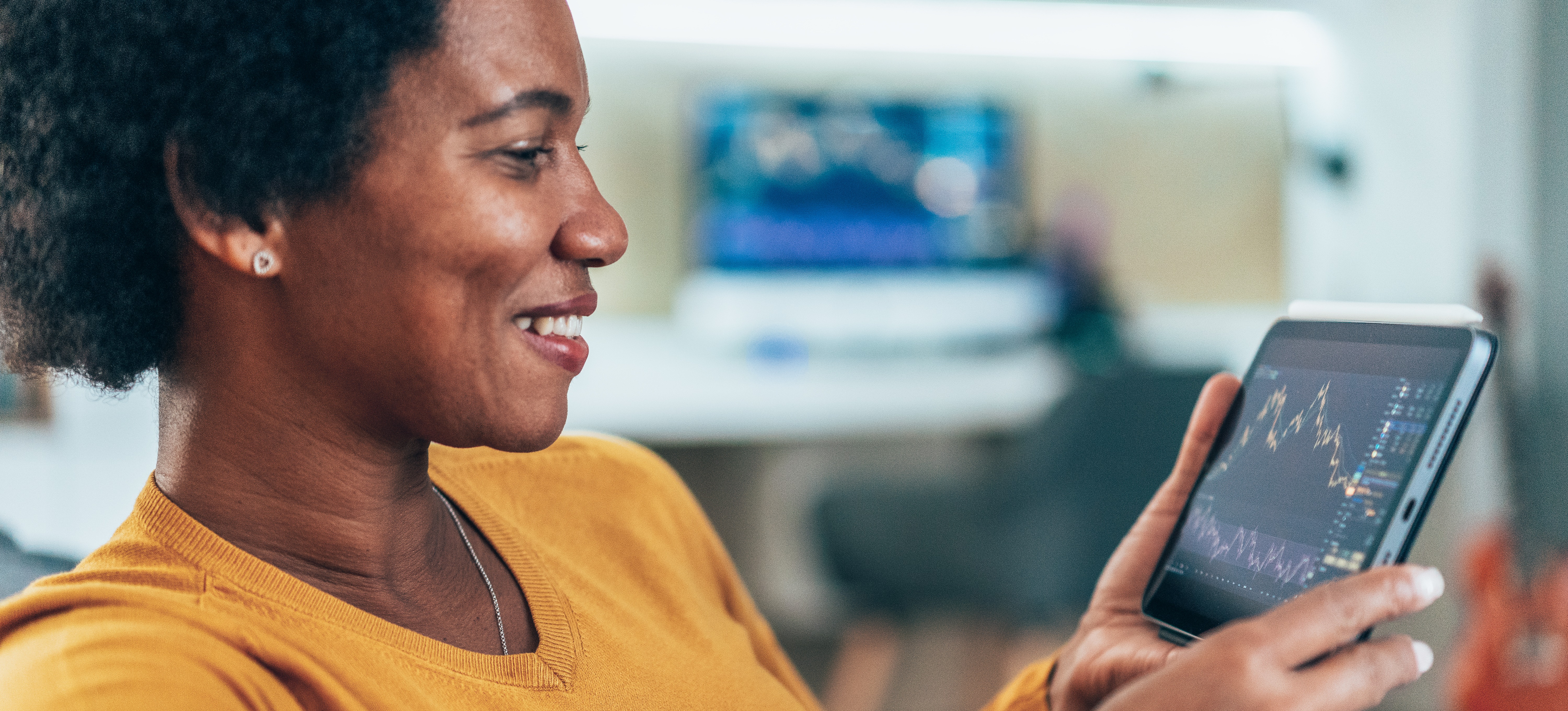 [Featured Image] A business person with a smile on their face is checking financial data on a digital tablet.
