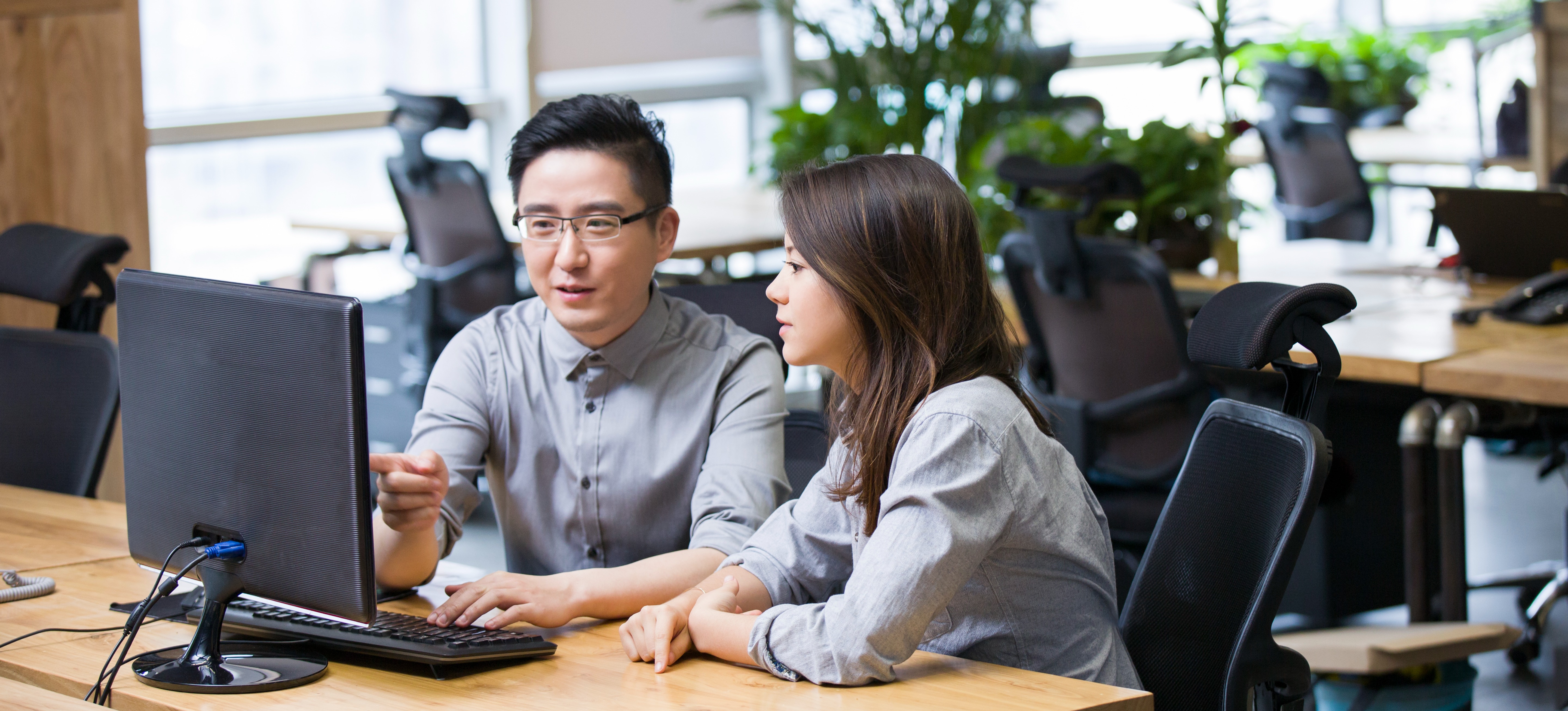 [Featured Image] Web development professionals in a work environment discuss how to improve web development skills while reviewing code on their computers.
