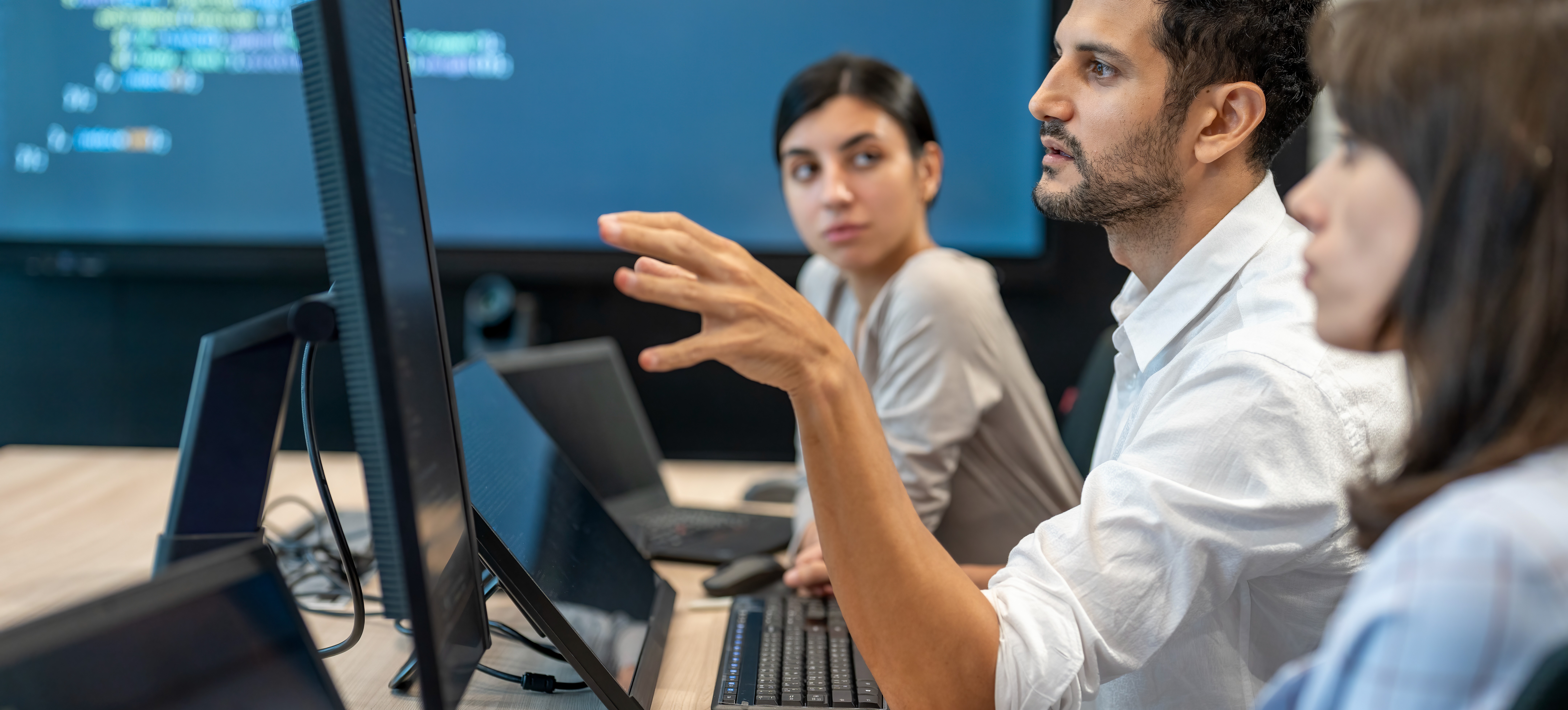 [Featured Image] AI professionals in a workplace discussing advanced AI detection tools, analyzing digital content for authenticity and transparency.