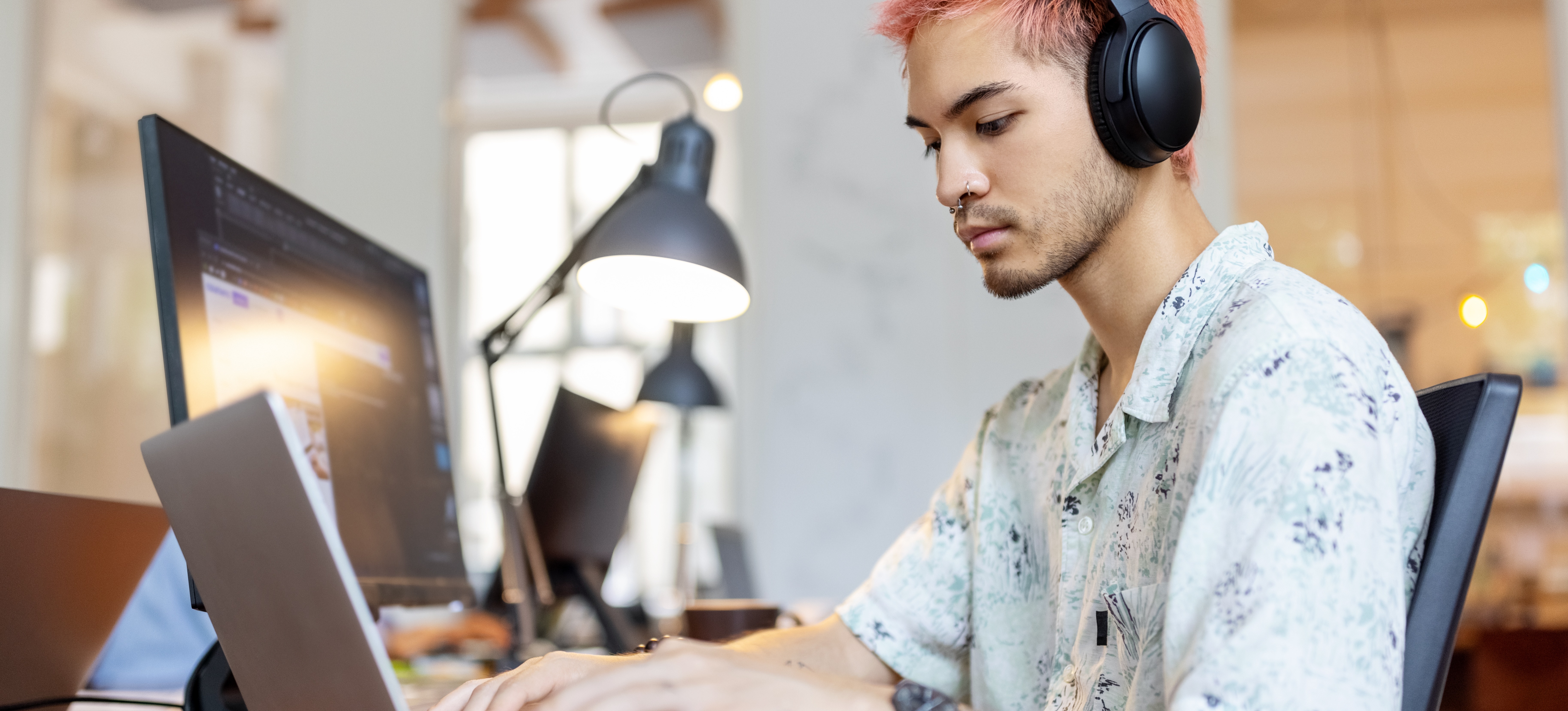 [Feature Image] An aspiring autonomous systems engineer wears headphones as they complete online coursework on their laptop.

