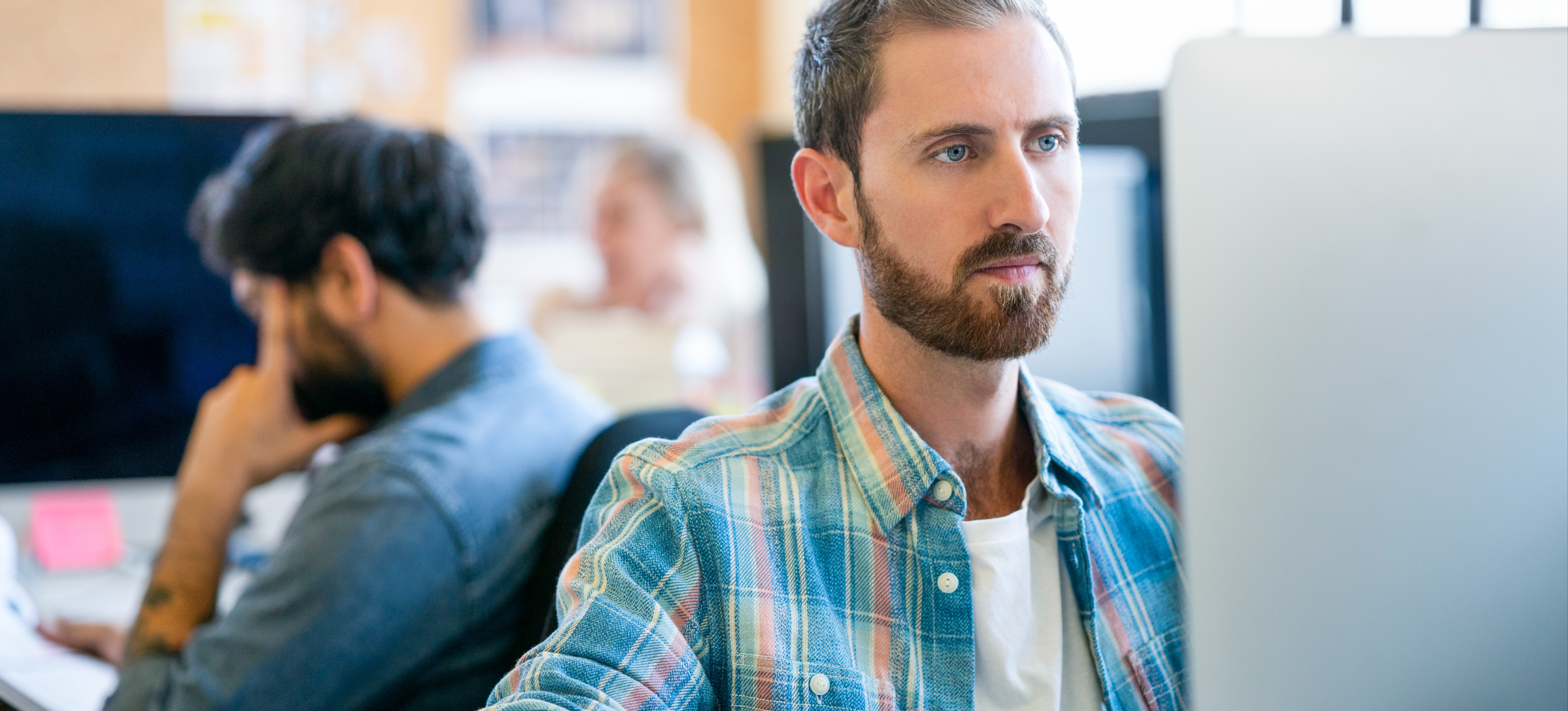 [Featured Image] A data scientist works with TensorFlow on their computer in a well-lit office while their colleagues work at nearby workstations.
